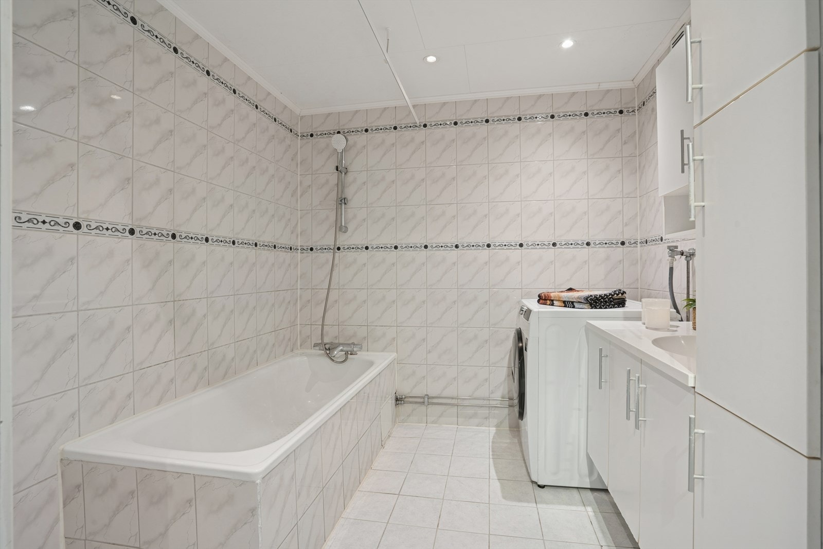 Baderom med badekar og opplegg for vaskemaskin. Galleribilde