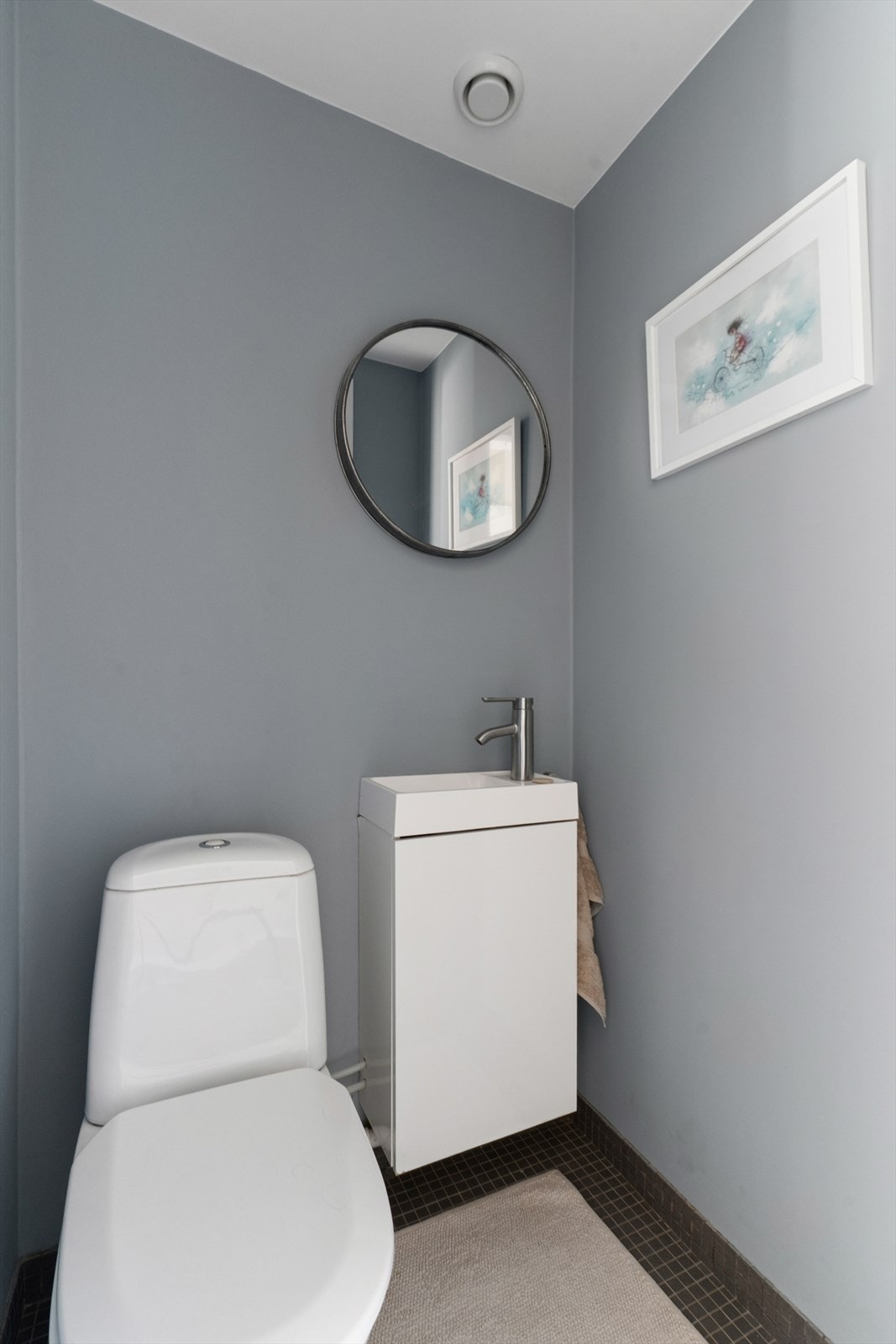 Separat toalettrom innredet med servant, servantskap, gulvstående klosett og speil over servant. Galleribilde