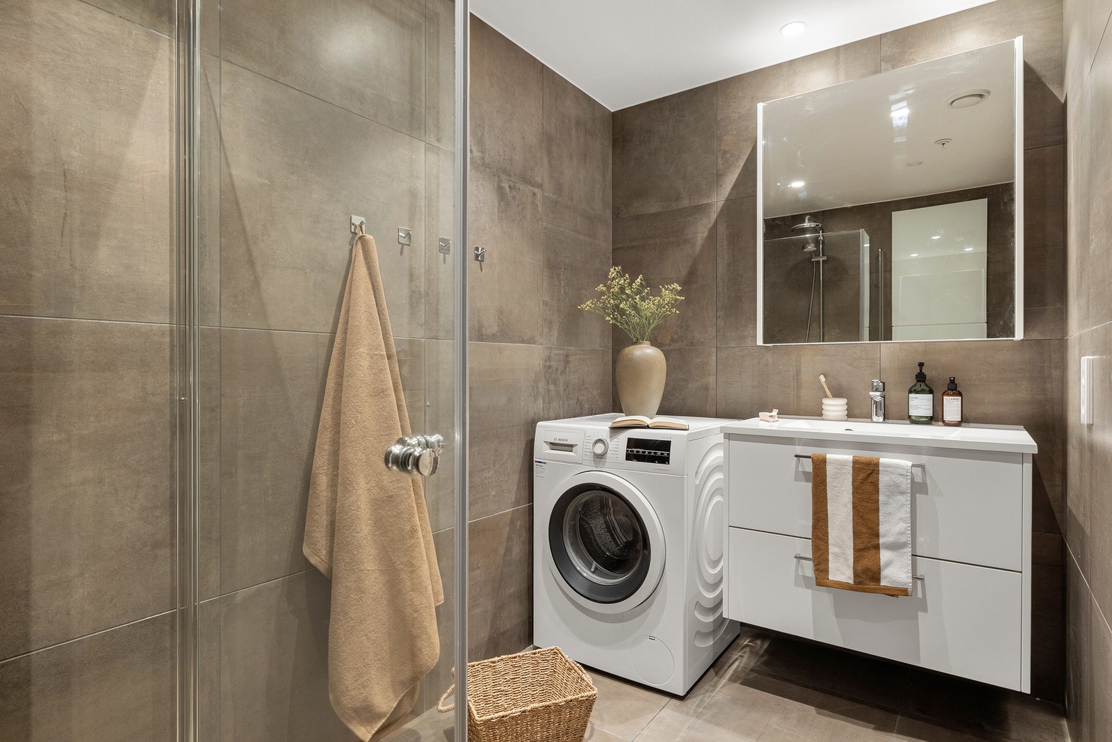 Badet på 4,3 kvm er helfliset med innfelte downlights i tak og gulvvarme. Galleribilde