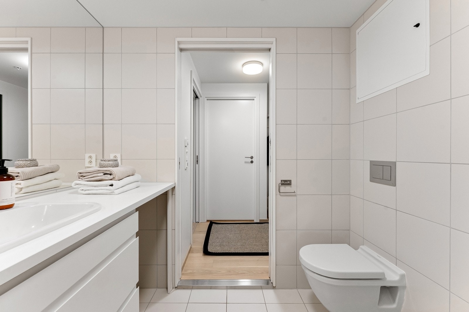 Badet har innredning med nedfelt servant, veggmontert toalett, dusjhjørne og opplegg for vaskemaskin. Galleribilde