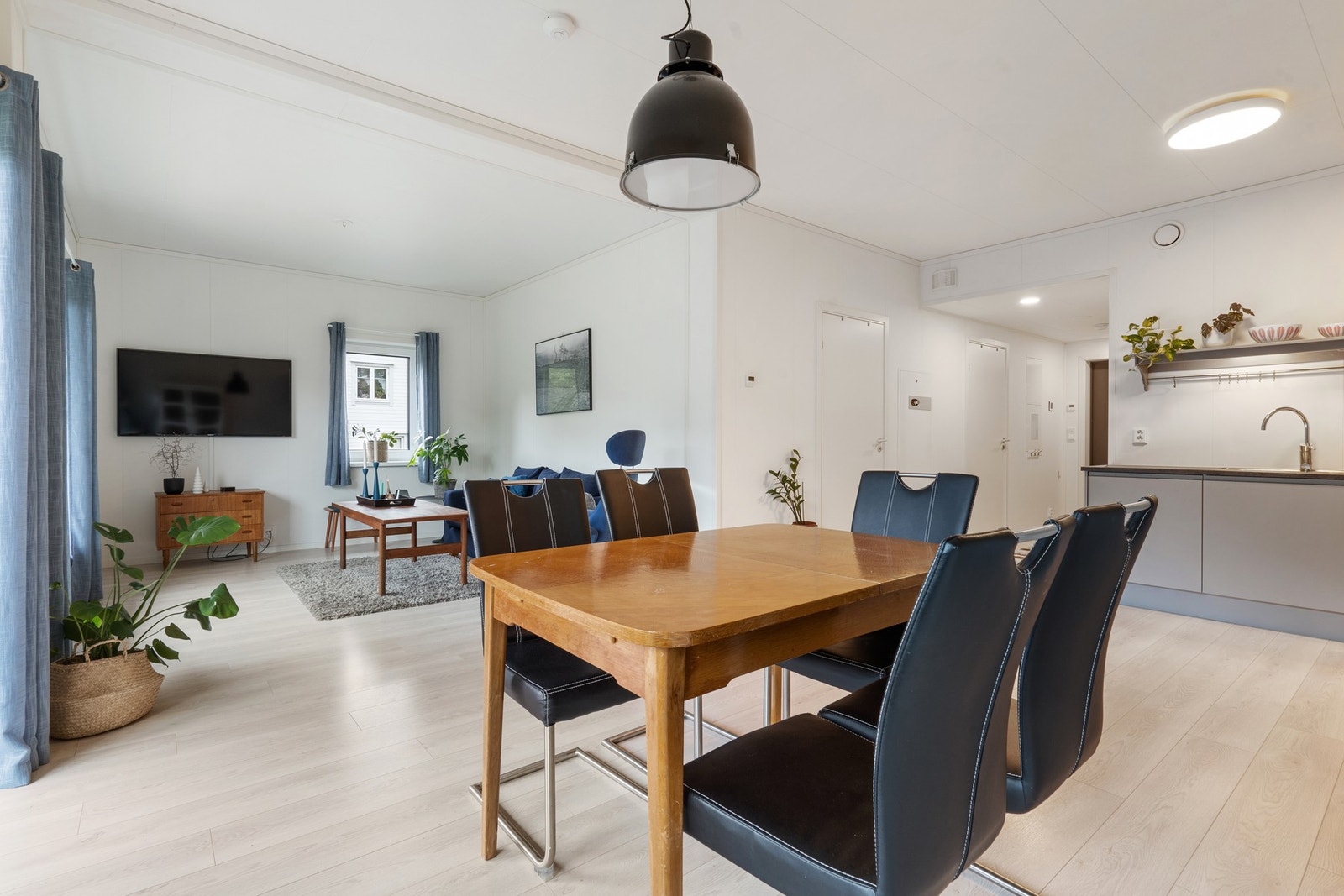 Åpen stue/kjøkken løsning med lysmalte vegger og laminat på gulvet. Galleribilde