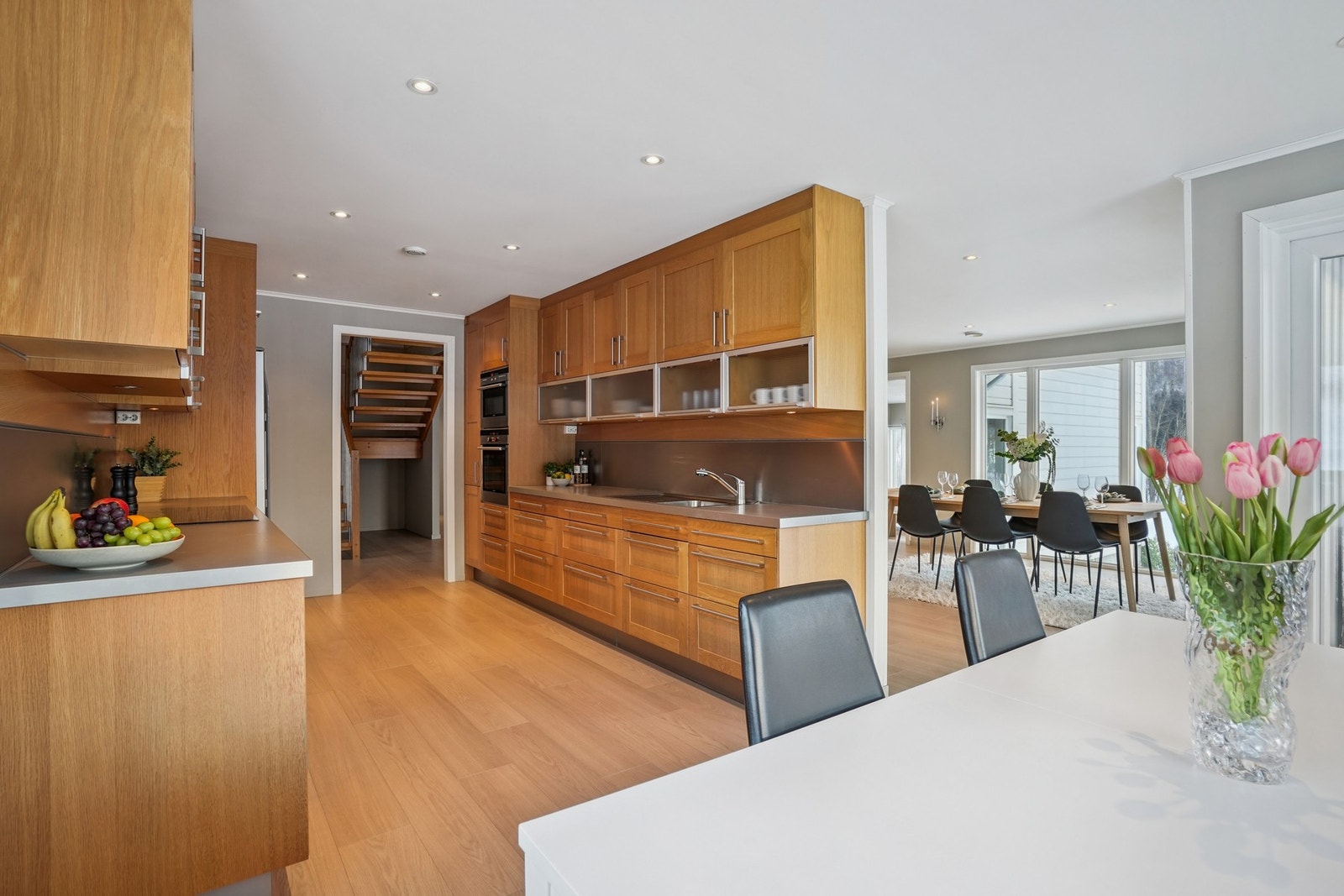 Pent kjøkken med profilerte fronter i heltre eik og stålfarget håndtak. Benkeplate av laminat. Galleribilde