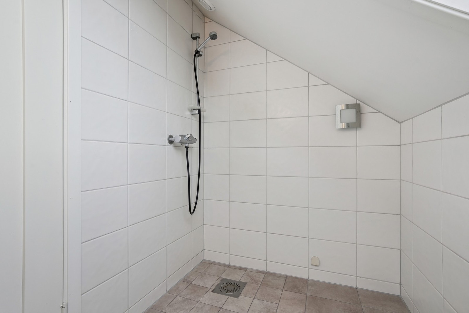 Utstyrt med vegghengt toalett og veggmontert dusjgarnityr på veggen. Galleribilde