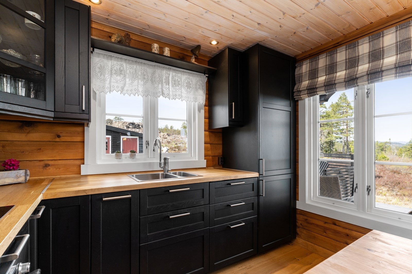 Kjøkkeninnredning og benkeplate er av heltre, og byr på en praktisk utforming med mye benkeplass, mørke profilerte fronter og Galleribilde