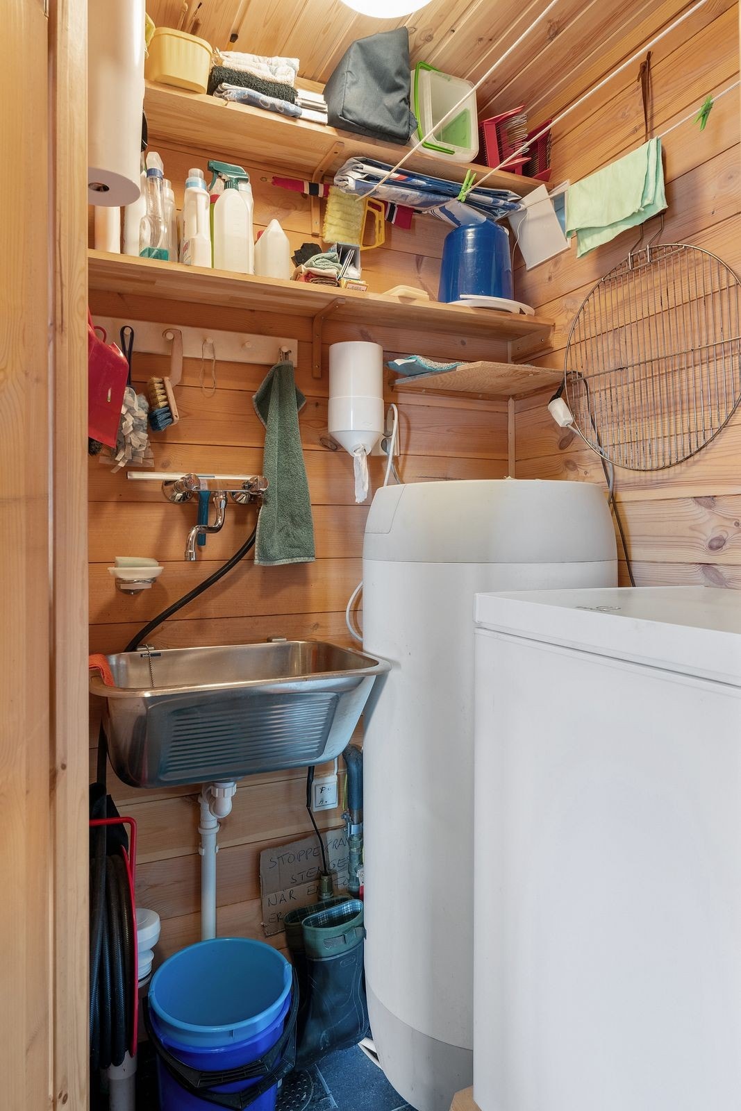 Teknisk rom med utslagsvask, varmtvannstank og fryser. Galleribilde