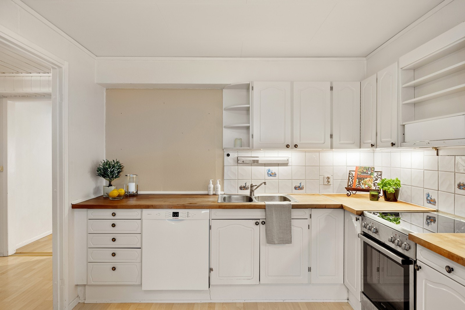 Pen kjøkkeninnredning med heltre benkeplate med nedfelt oppvaskkum med 1-greps blandebatteri. Det er opplegg for oppvaskmaskin, komfyr og det er tilkoblet en ventilator over kokeplass. Galleribilde