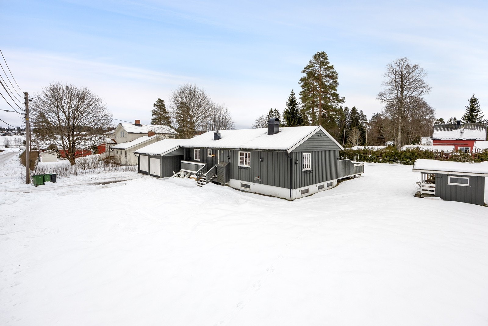 Selve tomten er tilnærmet flat med gressplen, diverse beplantning og asfaltert gårdsplass for parkering. Galleribilde
