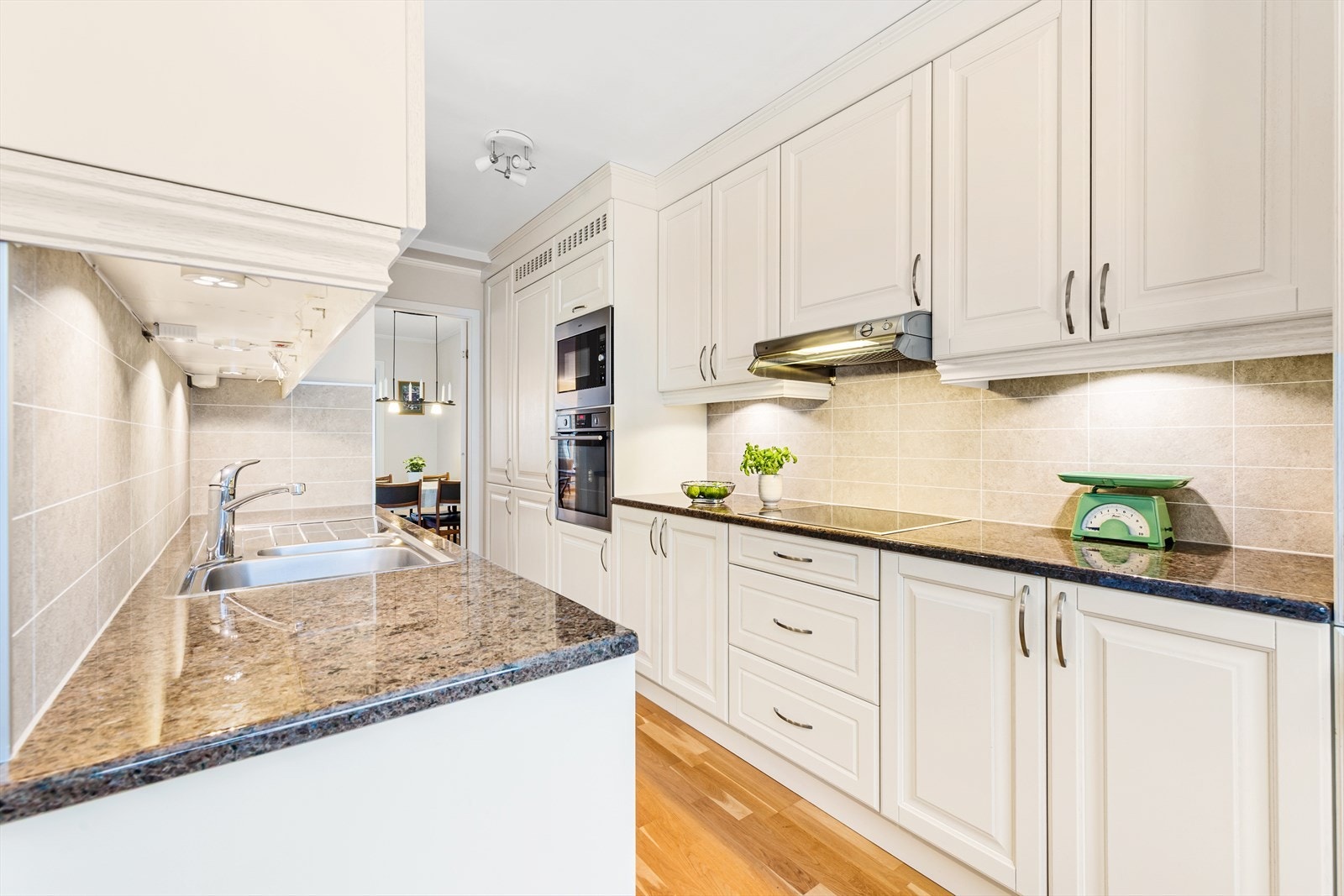 Lyst og funksjonelt kjøkken med kvalitetsdetaljer. Fremstår både romslig og praktisk, med tidløse profilerte fronter og en benkeplate i solid stein. Galleribilde