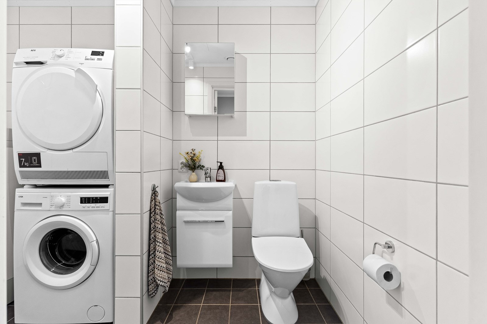 Flislagt baderom/vaskerom i 1. etasje med servant i servantskap, speilskap og toalett. Galleribilde