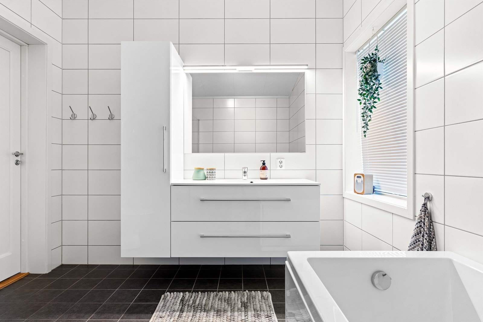 Flislagt baderom med servant i baderomsinnredning og speil. Galleribilde