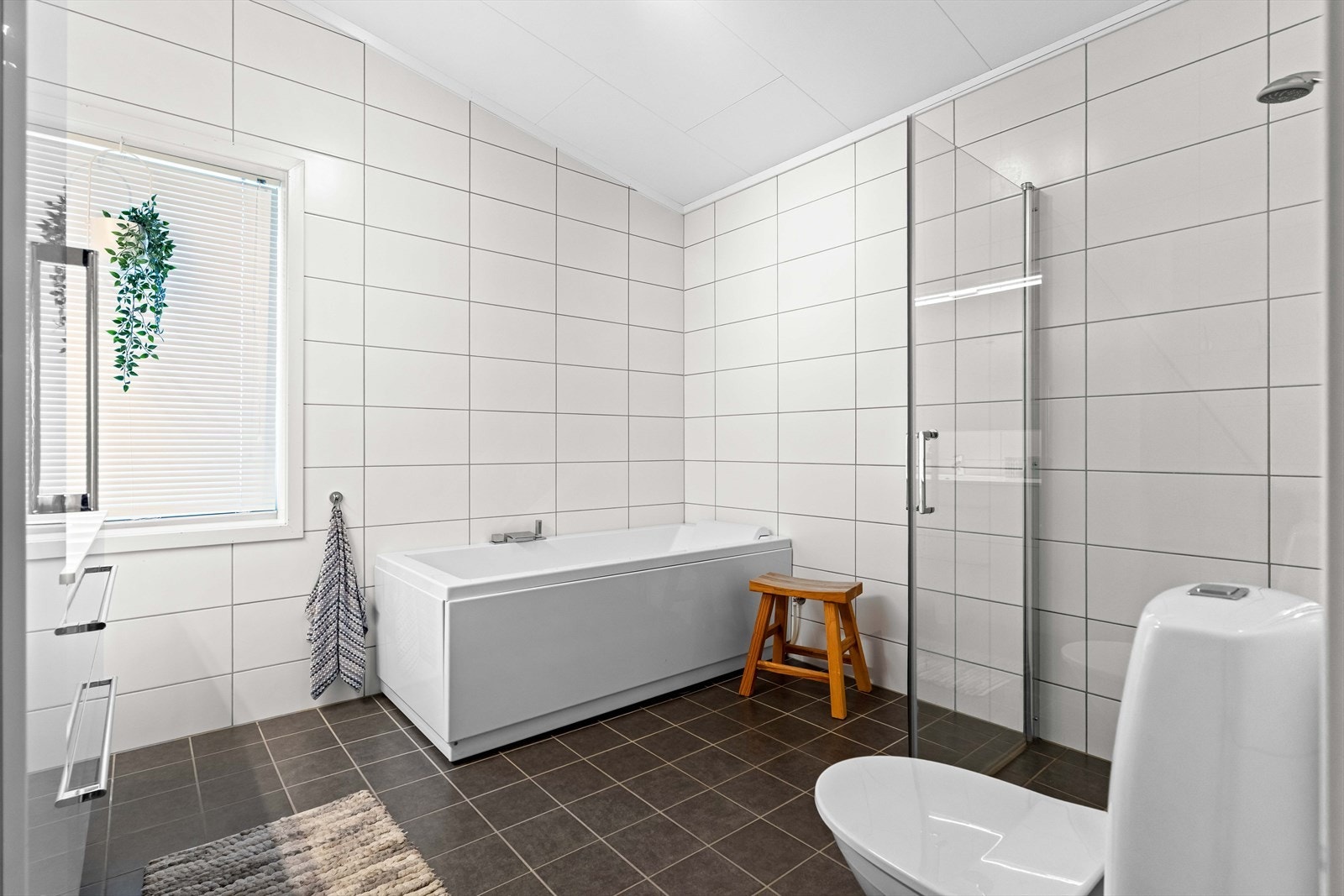 Badet er utstyrt med badekar, toalett og dusjhjørne med innfellbare glassdører. Galleribilde