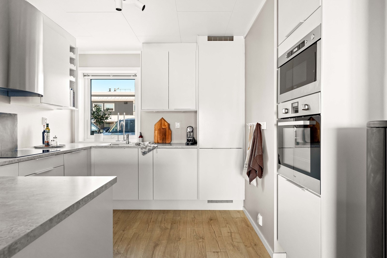 Flott kjøkken med hvite, glatte fronter og benkeplate av laminat. Galleribilde