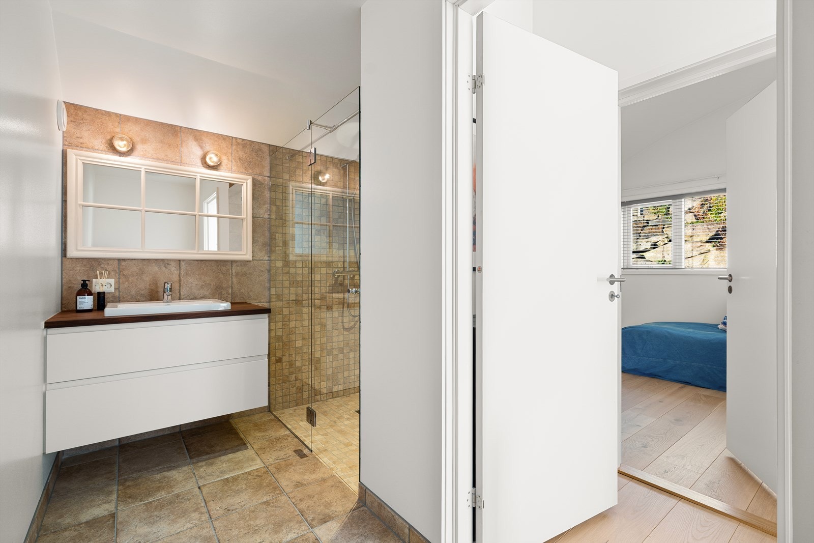 Etasjen har også et bad med flislagt gulv med varmekabler, fliser i stor dusjsone, vegghengt toalett og servant med blandebatteri. Galleribilde