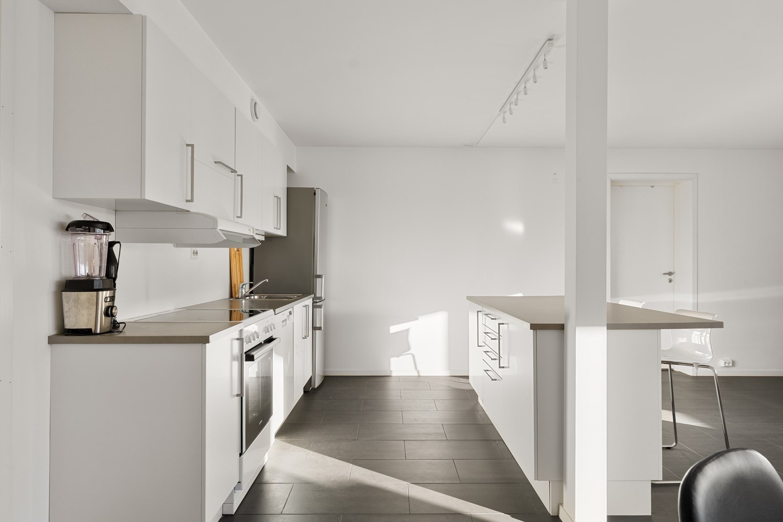 Kjøkkenet er innredet med moderne hvit innredning med slette fronter, kjøkkenøy og laminat benkeplate. Hvitevarer som oppvaskmaskin, komfyr med platetopp, ventilator samt frittstående kjøle- og fryseskap medfølger handelen. Galleribilde