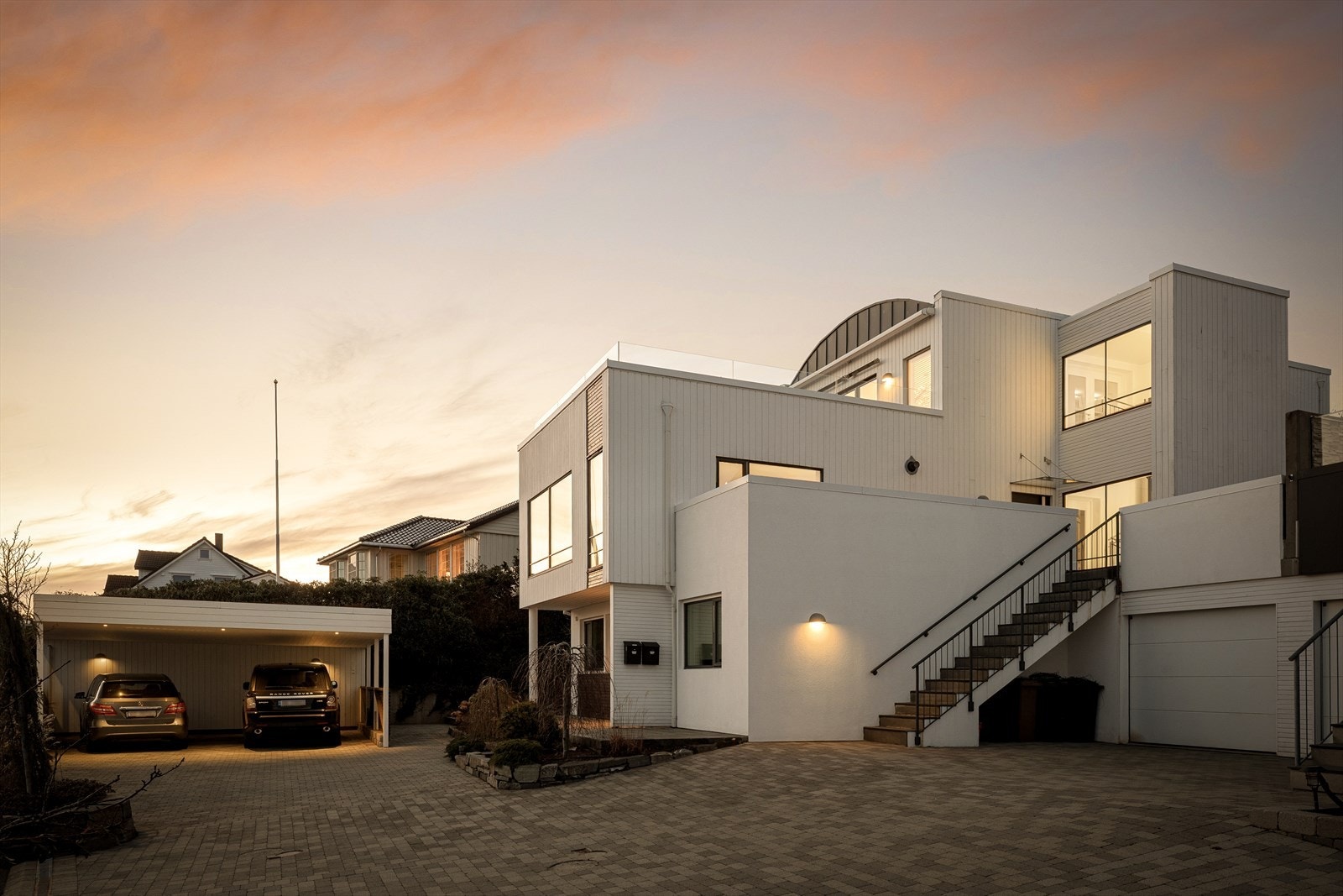 Romslig gårdsrom med belegningsstein og skifer, omgitt av frodige bed med busker og trær. Galleribilde