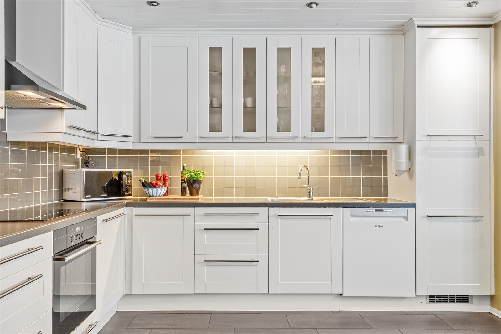 Innredningen har lyse profilerte fronter, laminert benkeplate med nedfelt oppvaskkum og flotte fliser i benkeryggen. Praktisk med belysning under de takhøye overskapene i tillegg til downlights i himlingen. Galleribilde