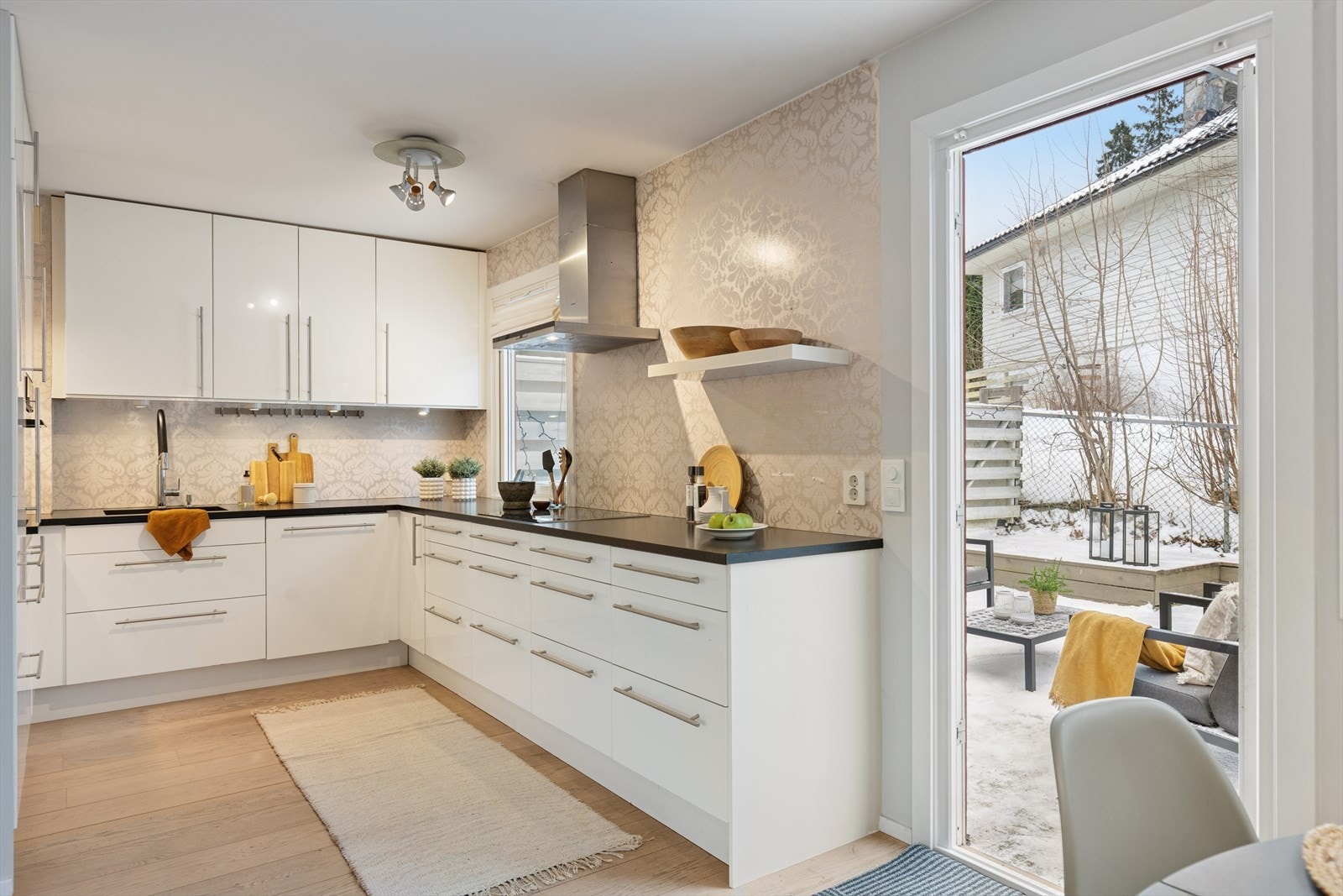 Kjøkkenet er moderne og stilrent, innredet med slette høyglansfronter, benkeplate i stein og underlimt oppvaskkum i sort kompositt. Galleribilde