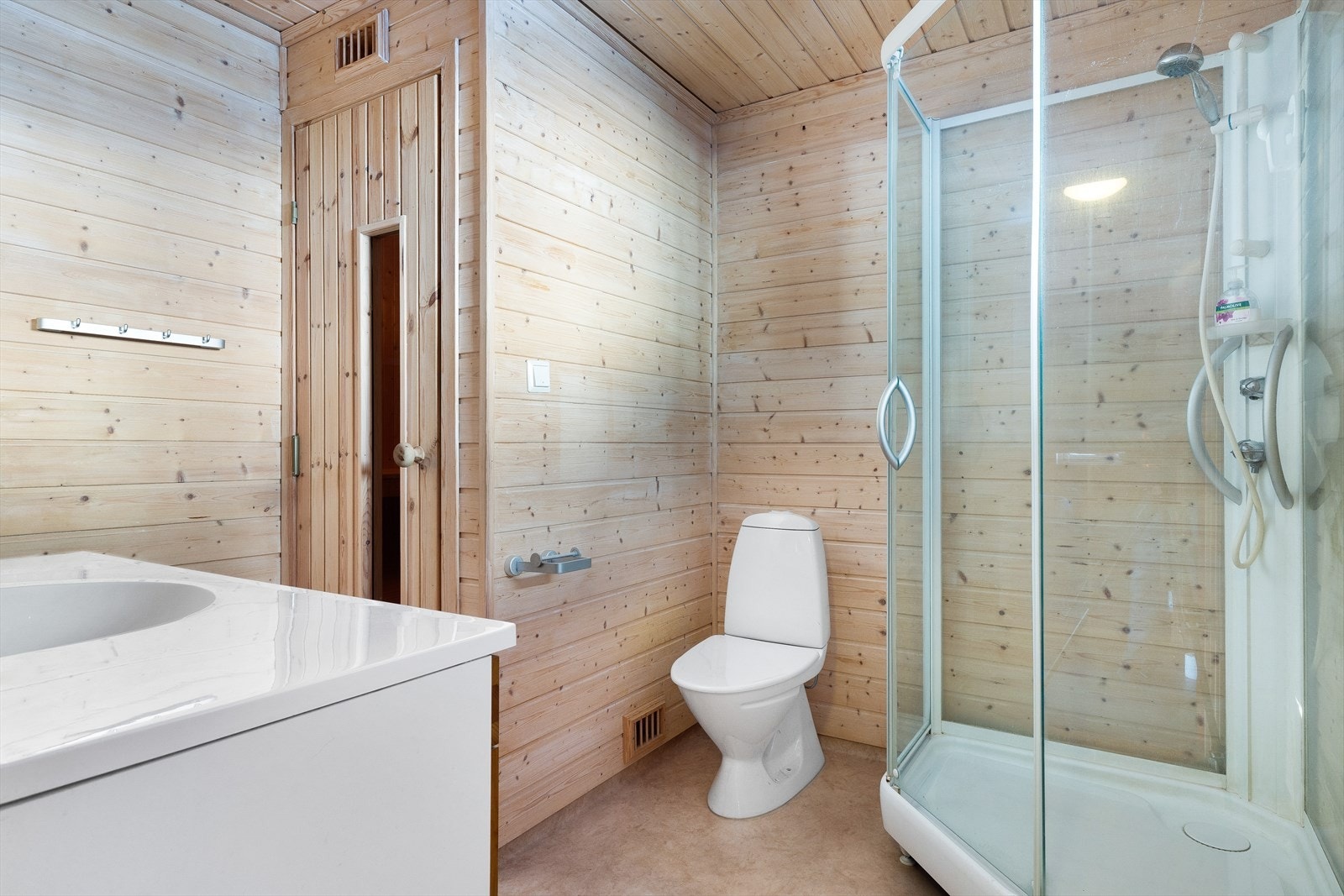 Badet har vinylbelegg på gulv og panel på vegger. Innredet med toalett, servant i baderomsmøbel og dusjkabinett. Galleribilde