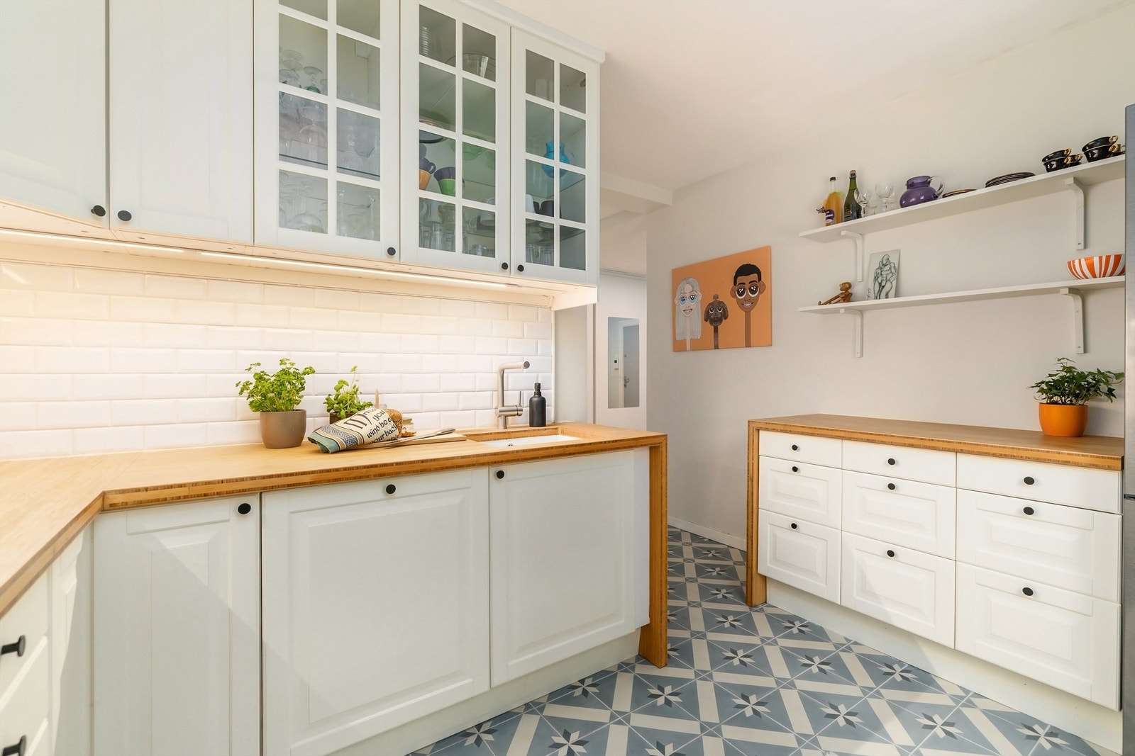 Kjøkkeninnredning med hvite, profilerte fronter, benkeplate av bambus og underlimt oppvaskkum med ett-greps kjøkkenarmatur Galleribilde