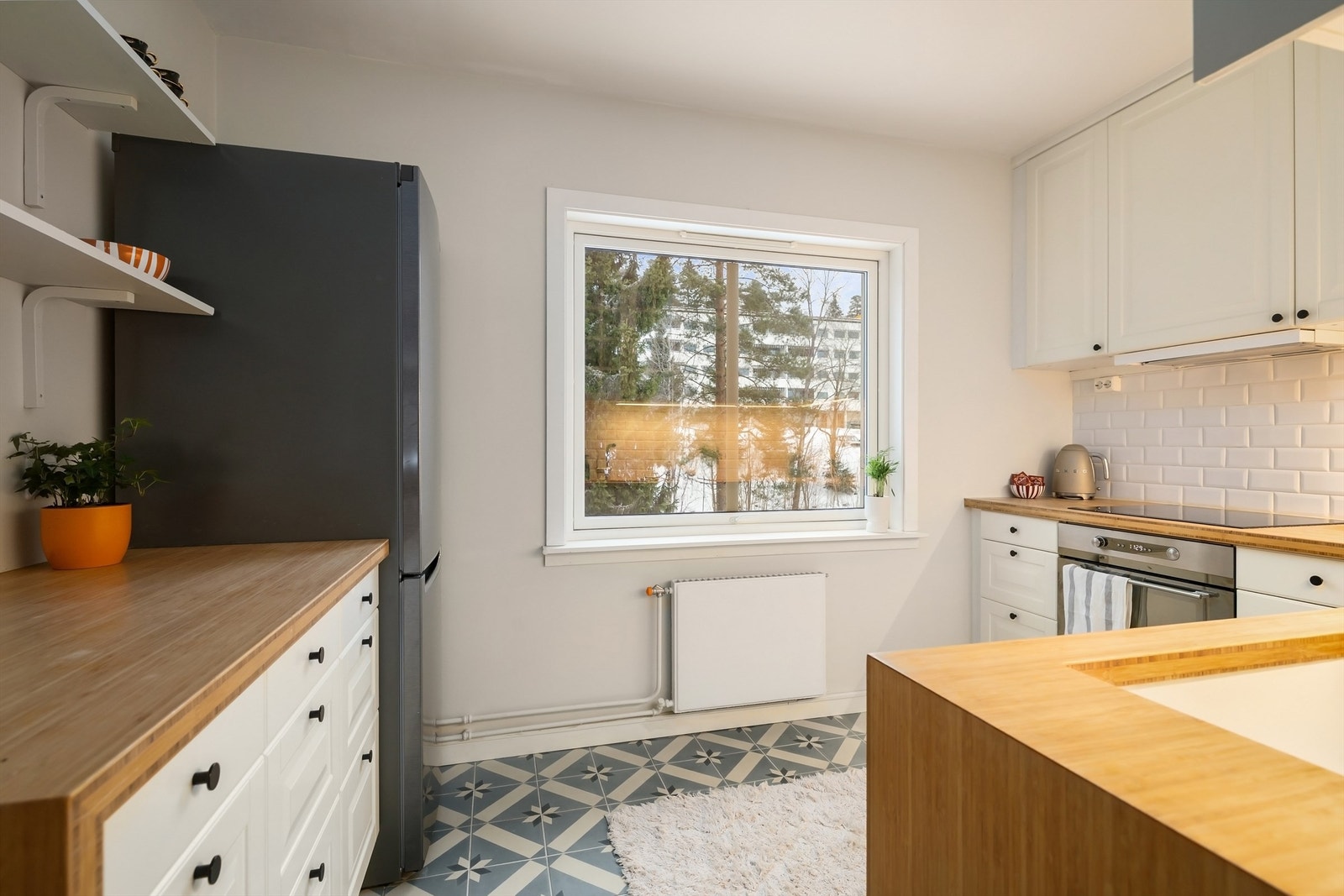 Integrerte hvitevarer som stekeovn, platetopp med ventilator over og oppvaskmaskin samt kjøleskap plassert i nisje Galleribilde