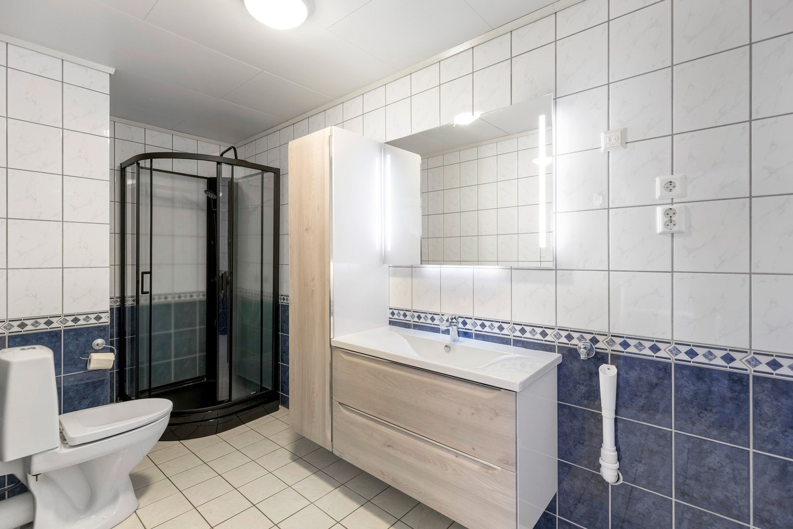 Badet har varmekabler i gulv og inneholder baderomsinnredning fra 2019, dusjkabinett fra 2025, toalett fra 2020, samt opplegg for vaskemaskin. Galleribilde