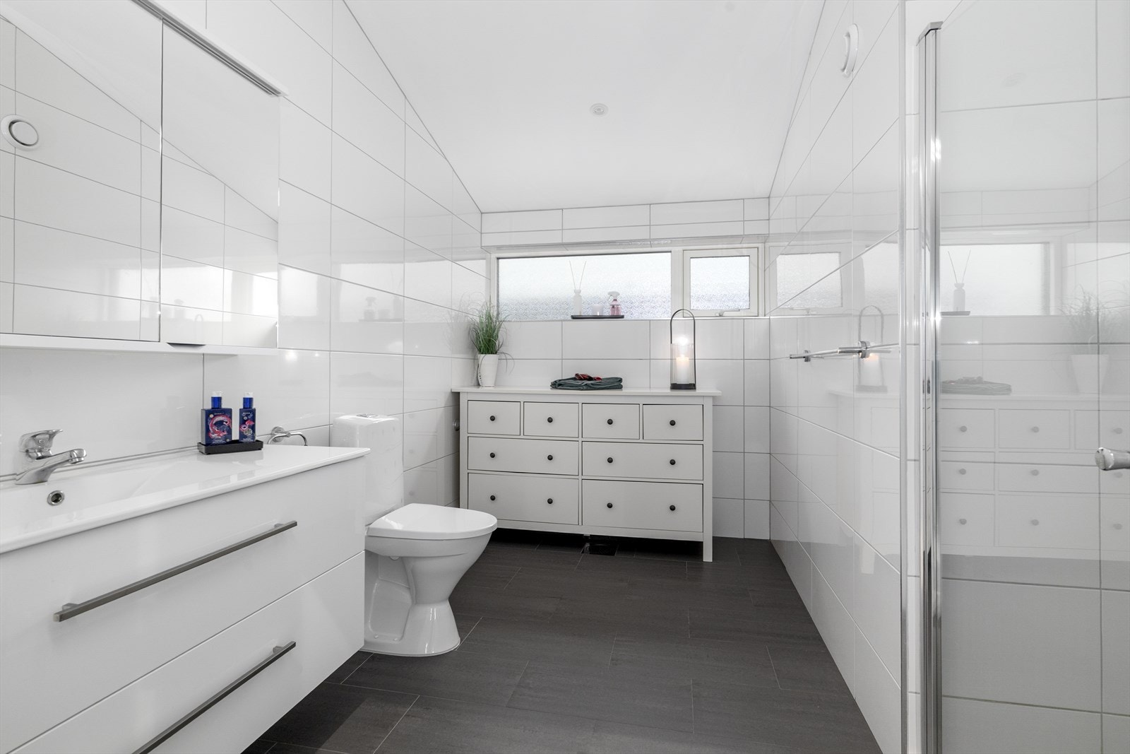 Pent baderom i 2. etasje som inneholder heldekkende servant, overskap med speilfronter, gulvmontert toalett og dusjhjørne. Galleribilde