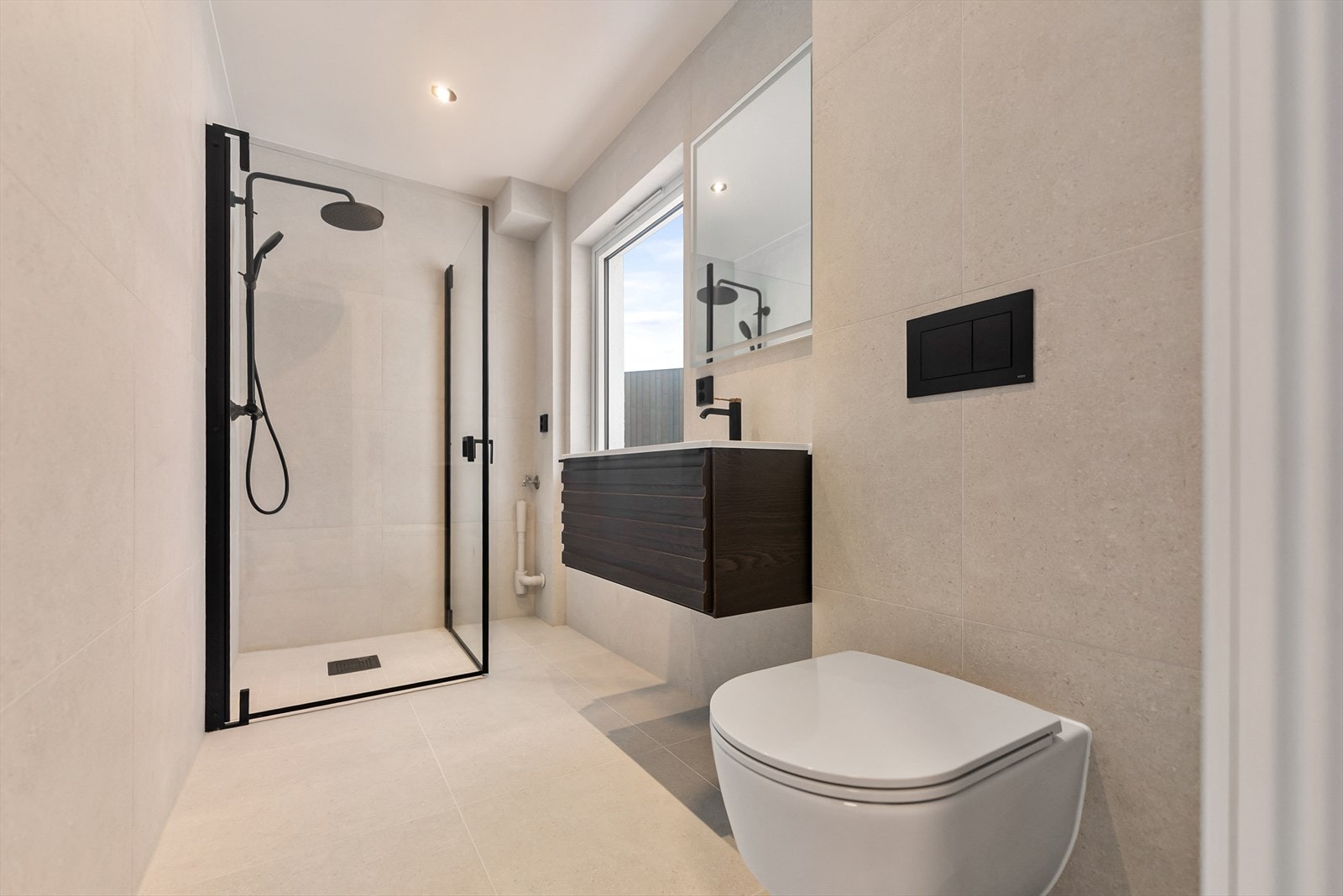 Moderne bad med minimalistisk design. Dusj med glassvegg, vegghengt toalett og stilrent servantskap. Galleribilde