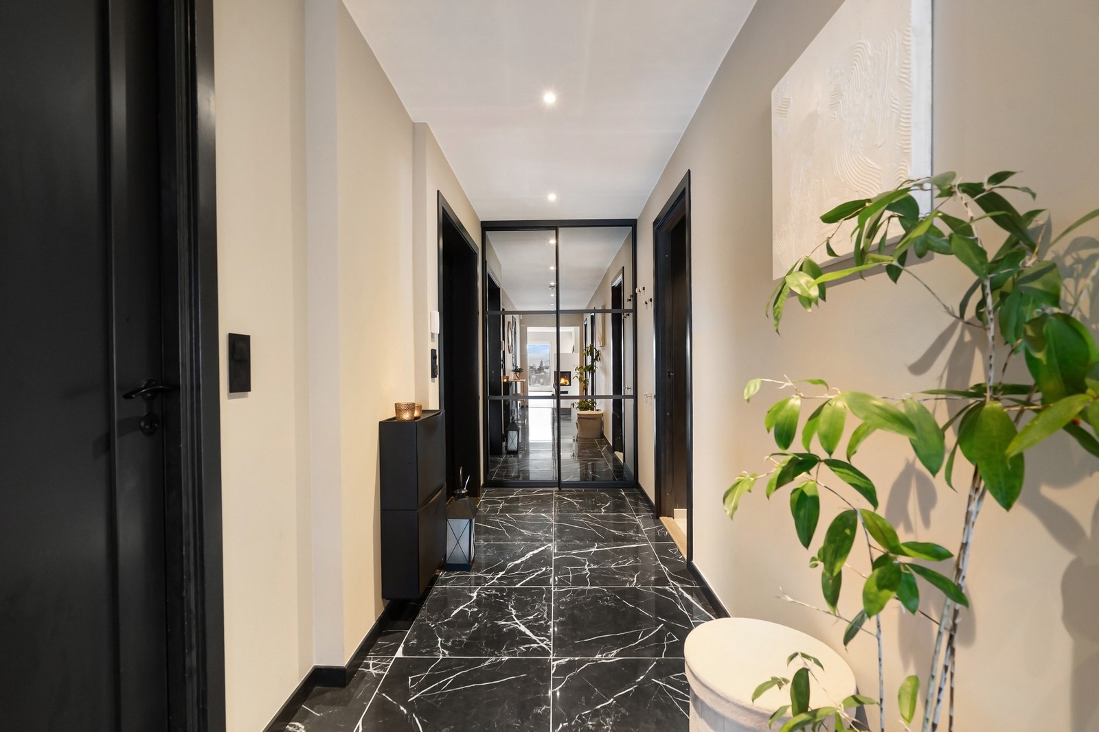 En romslig og velorganisert entré med store marmorfliser, behagelig gulvvarme og skyvedørsgarderobe med speilfronter. Galleribilde