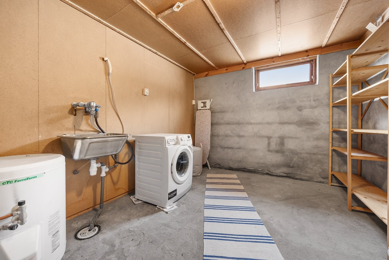 Praktisk vaskekjeller med betonggulv, sluk og opplegg for vaskemaskin. Galleribilde