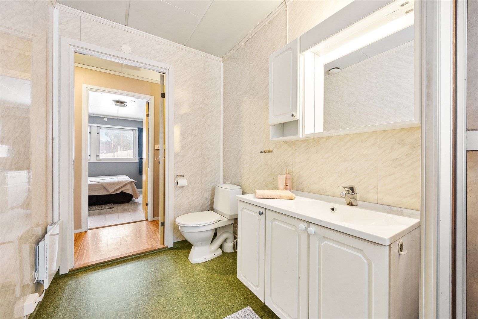 Badet består av servant med skap, toalett og dusjkabinett. Galleribilde