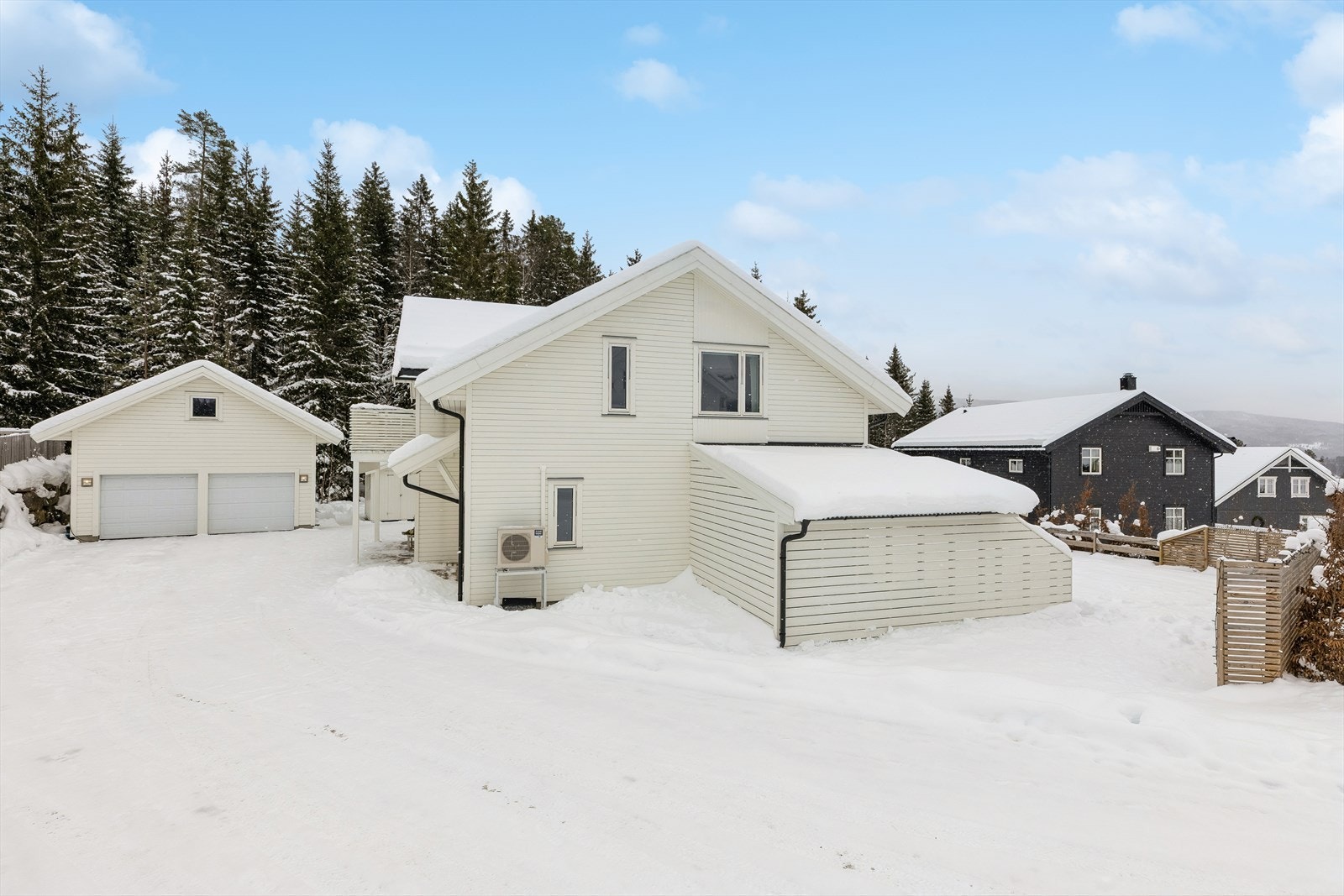 Dobbelgarasje fra 2018 med innredet loft (isolert) for ekstra lagring. Elbillader. Den asfalterte gårdsplassen gjør uttrykket rent og ryddig og bidrar samtidig til en praktisk og lettstelt uteplass. Her er det god plass for både parkering, sykler og lek Galleribilde