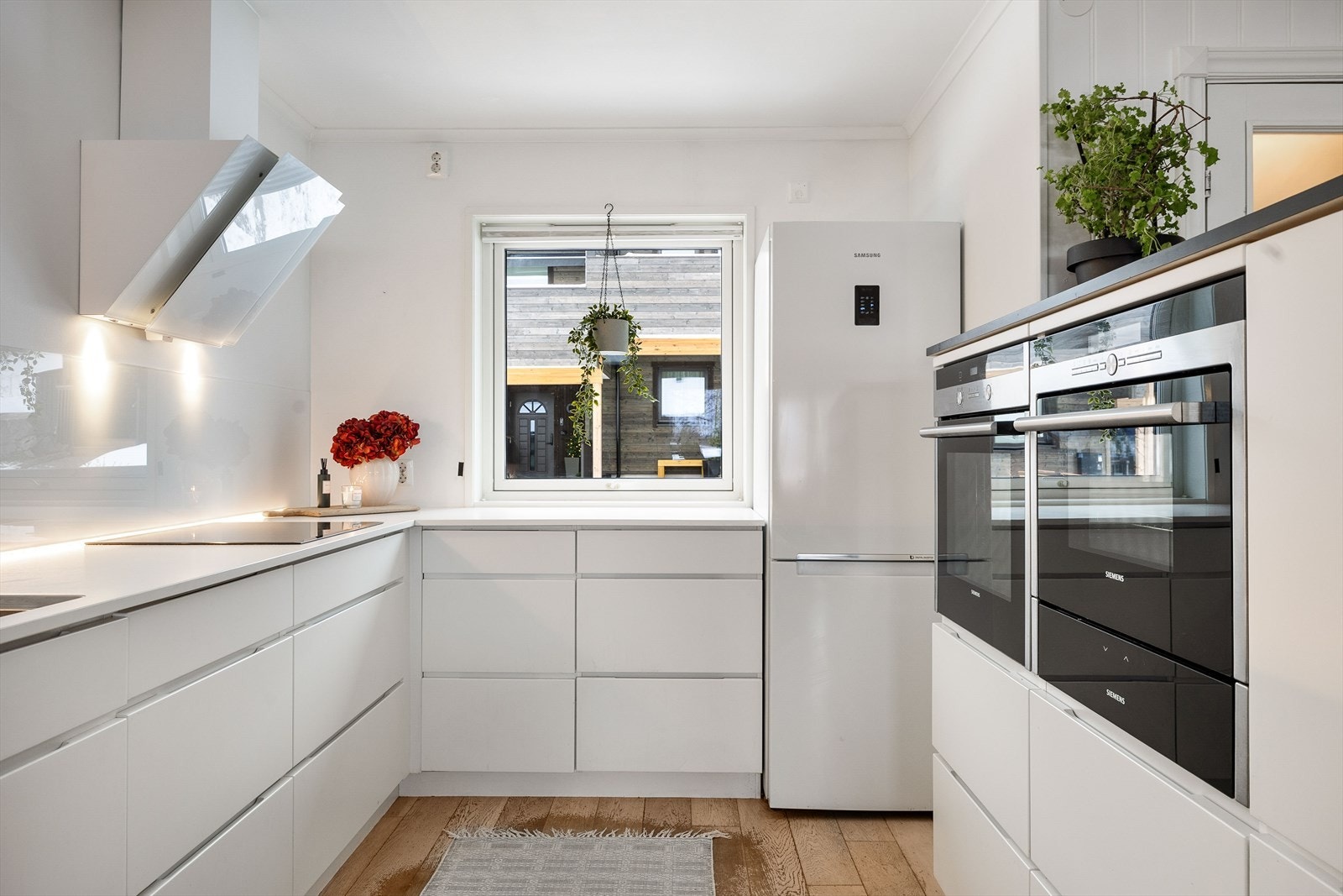 Kjøkkenet har innredning med glatte fronter og benkeplate i laminat Galleribilde