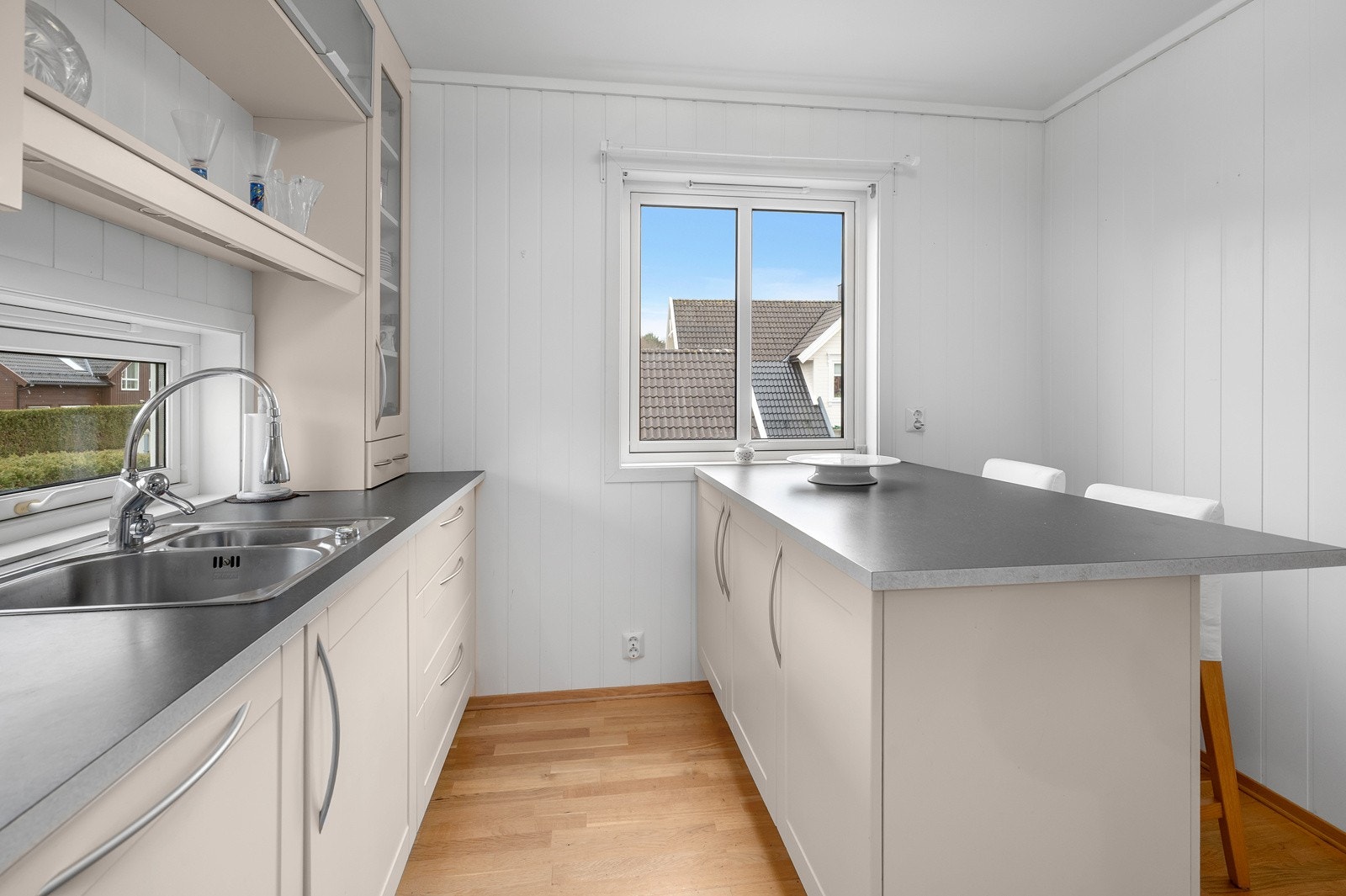 Kjøkkenet er stilrent med lyse fronter og grå benkeplate Galleribilde