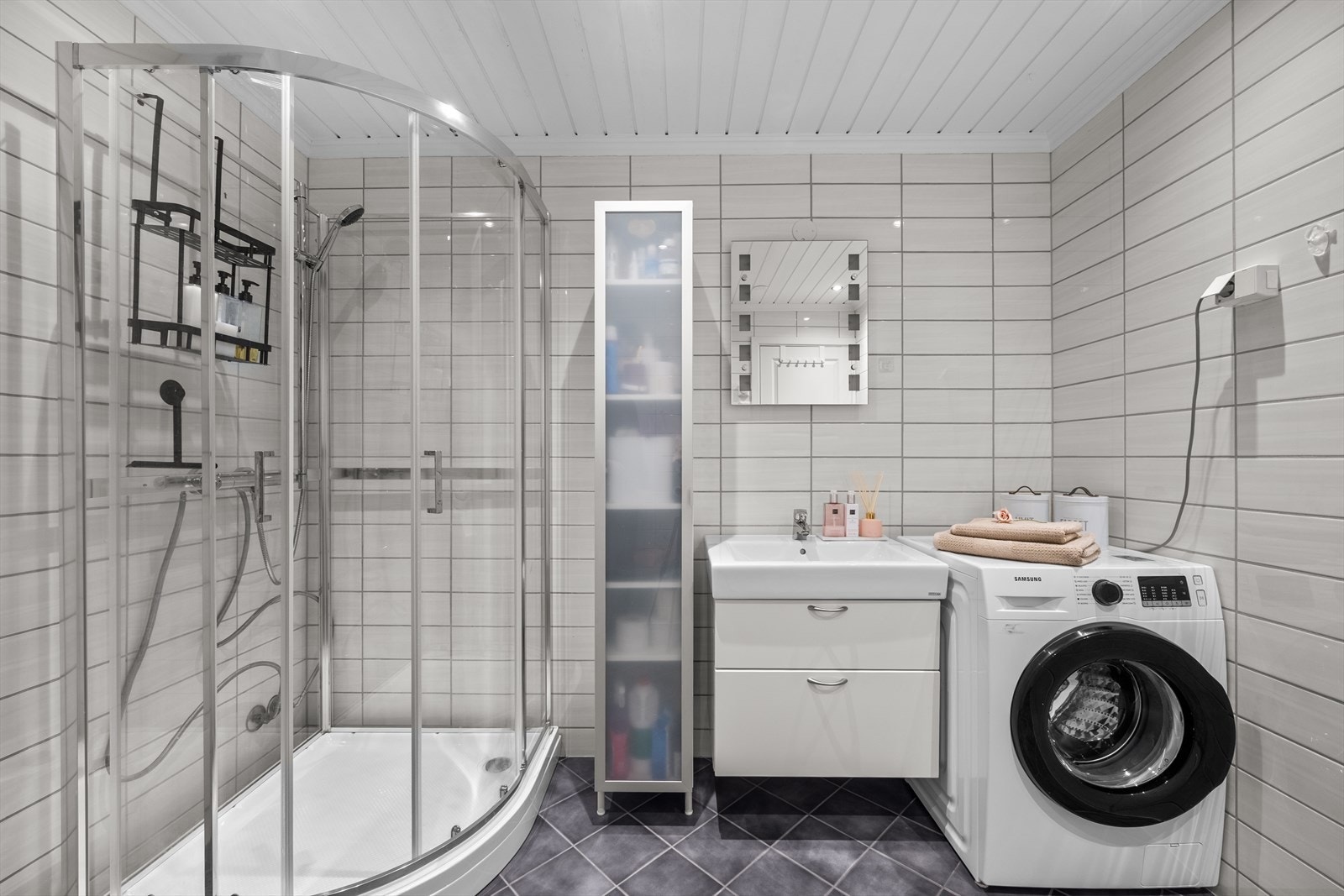 Badet er utstyrt med innredning med servant, speil med belysning, veggmontert toalett og dusjkabinett i herdet glass fra 2025. Badet har naturlig ventilering. Galleribilde