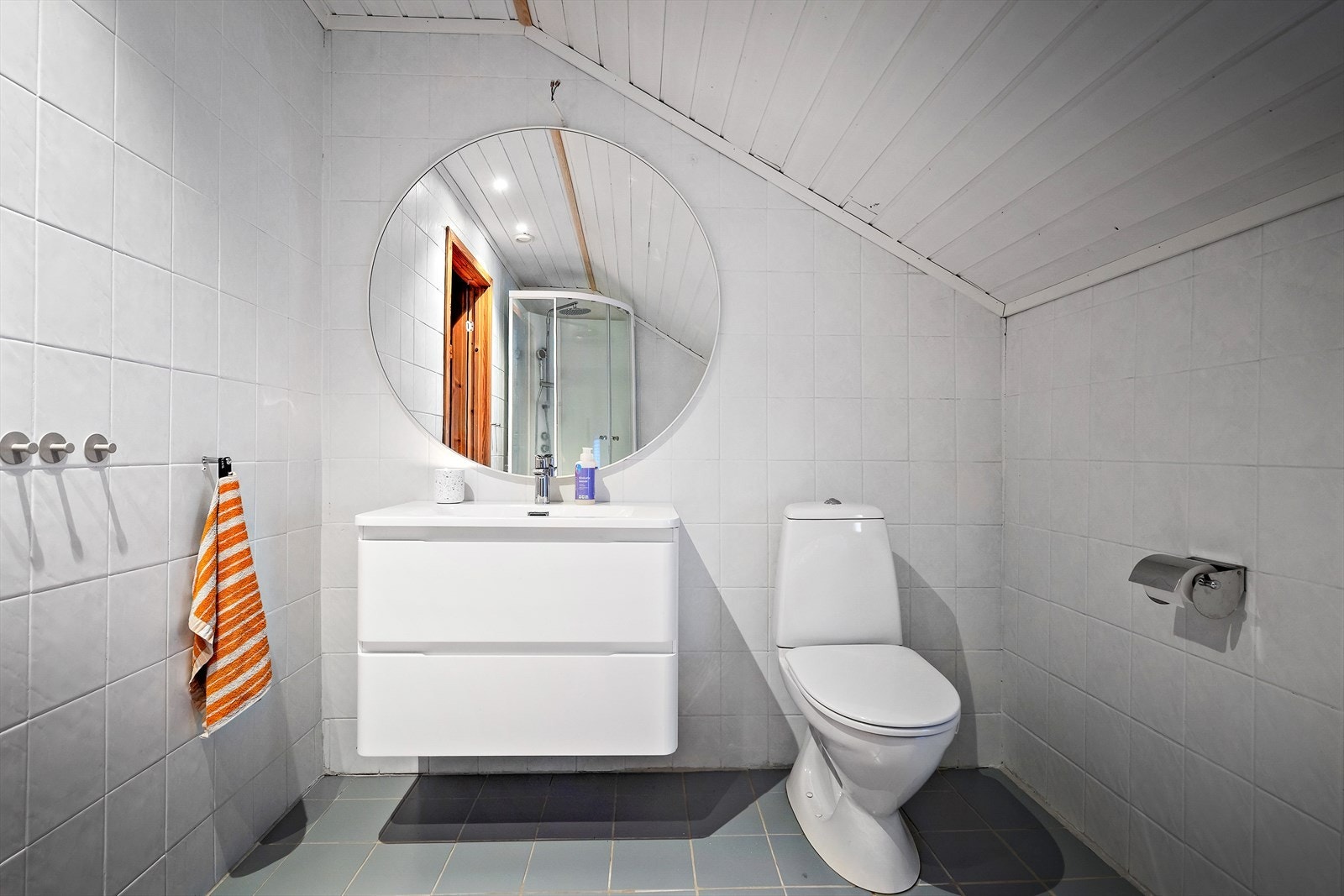 Flislagte vegger og malt trepanel i tak gir en robust overflate på badet. Galleribilde