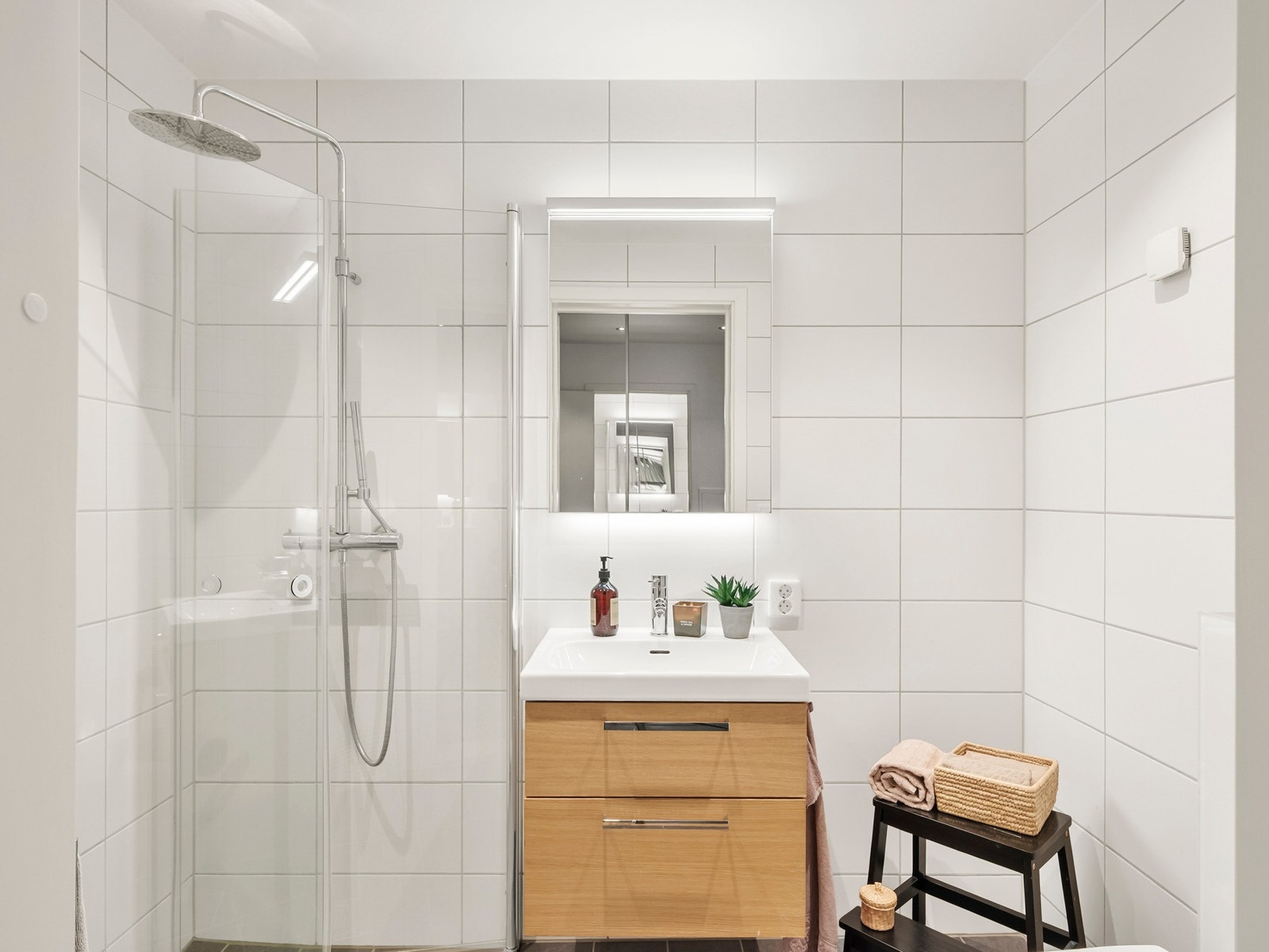 Fra entreèn kommer man til boligens første bad. Tidløst og flislagt baderom med vannbåren gulvvarme og moderne innredning. Galleribilde