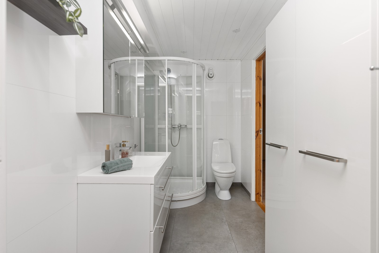 Baderom fra 2015 med flislagt gulv, dusjkabinett, wc og servant samt speil med oppbevaring. Galleribilde