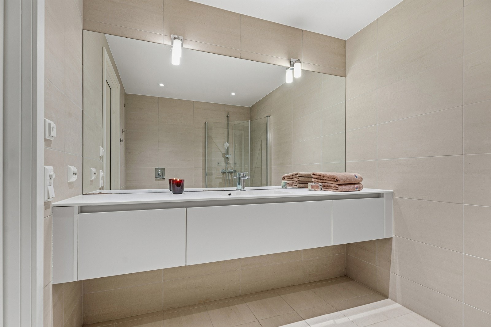 Lekkert baderom bestående av vegghengt baderomsinnredning, toalett og dusjhjørne med innfellbare dusjdører. Galleribilde