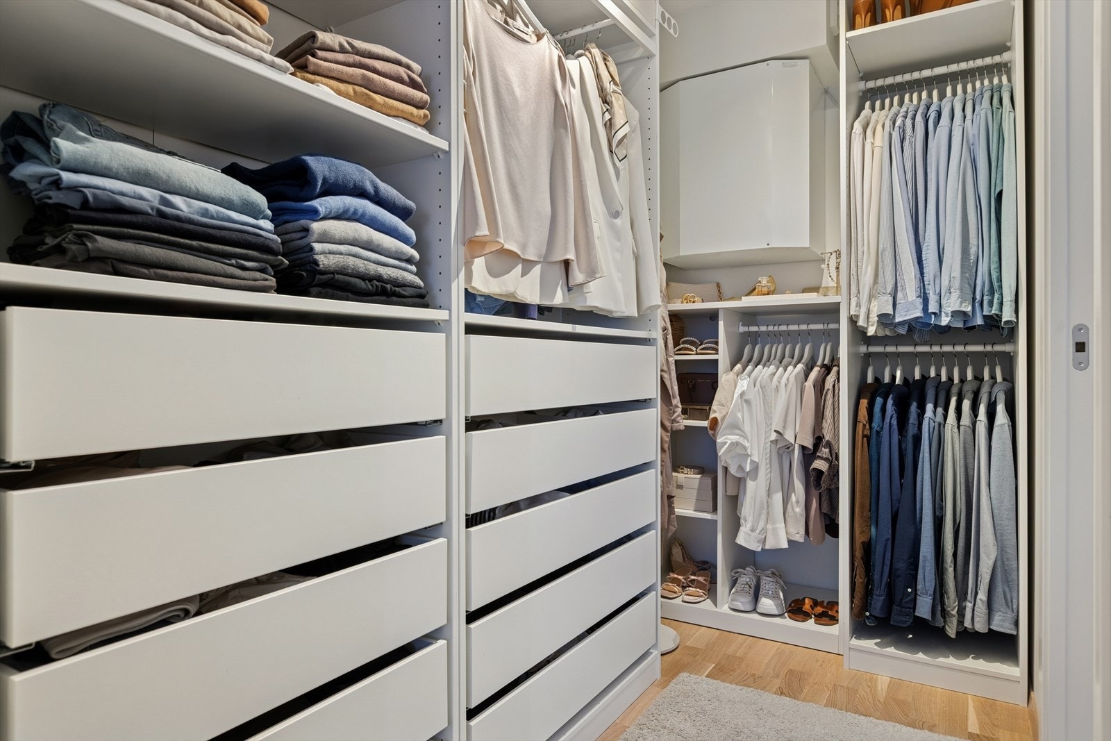 Ryddig og praktisk walk-in closet med skap, hyller og romslig plass med, en smart og organisert oppbevaringsløsning som gir full oversikt over garderoben. Galleribilde