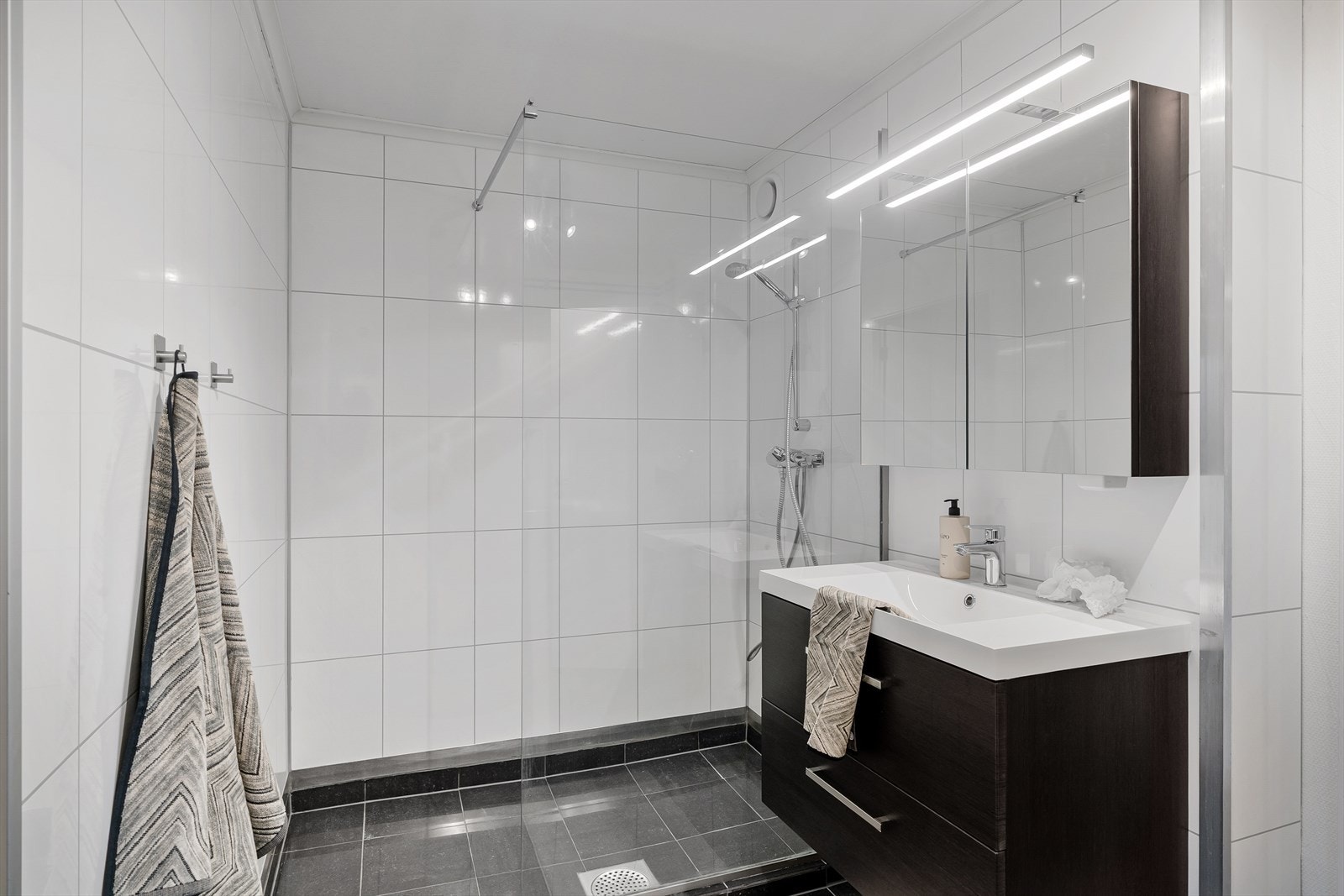 Flott bad med fliser på gulv og baderomsplater på veggene. Gulvvarme Galleribilde