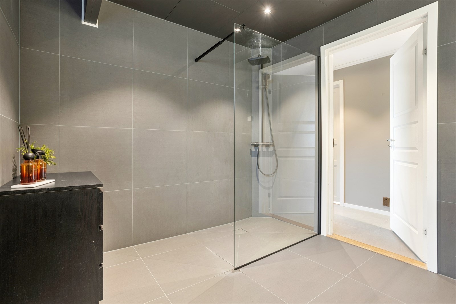 Baderommet er av svært god størrelse, og består av vegghengt toalett, stort dusjhjørne, servant med baderomsinnredning og LED-speilbelysning over Galleribilde