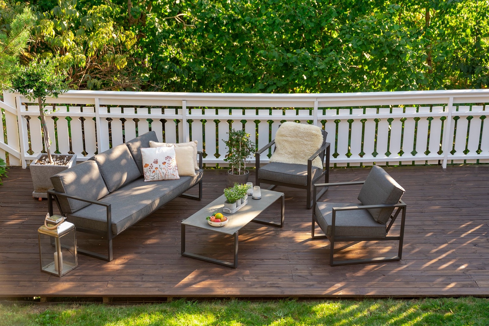 Terrassen ligger usjenert til med tett vegetasjon og hvit stakitt som rammer inn hagen på en trygg og barnevennlig måte. Galleribilde