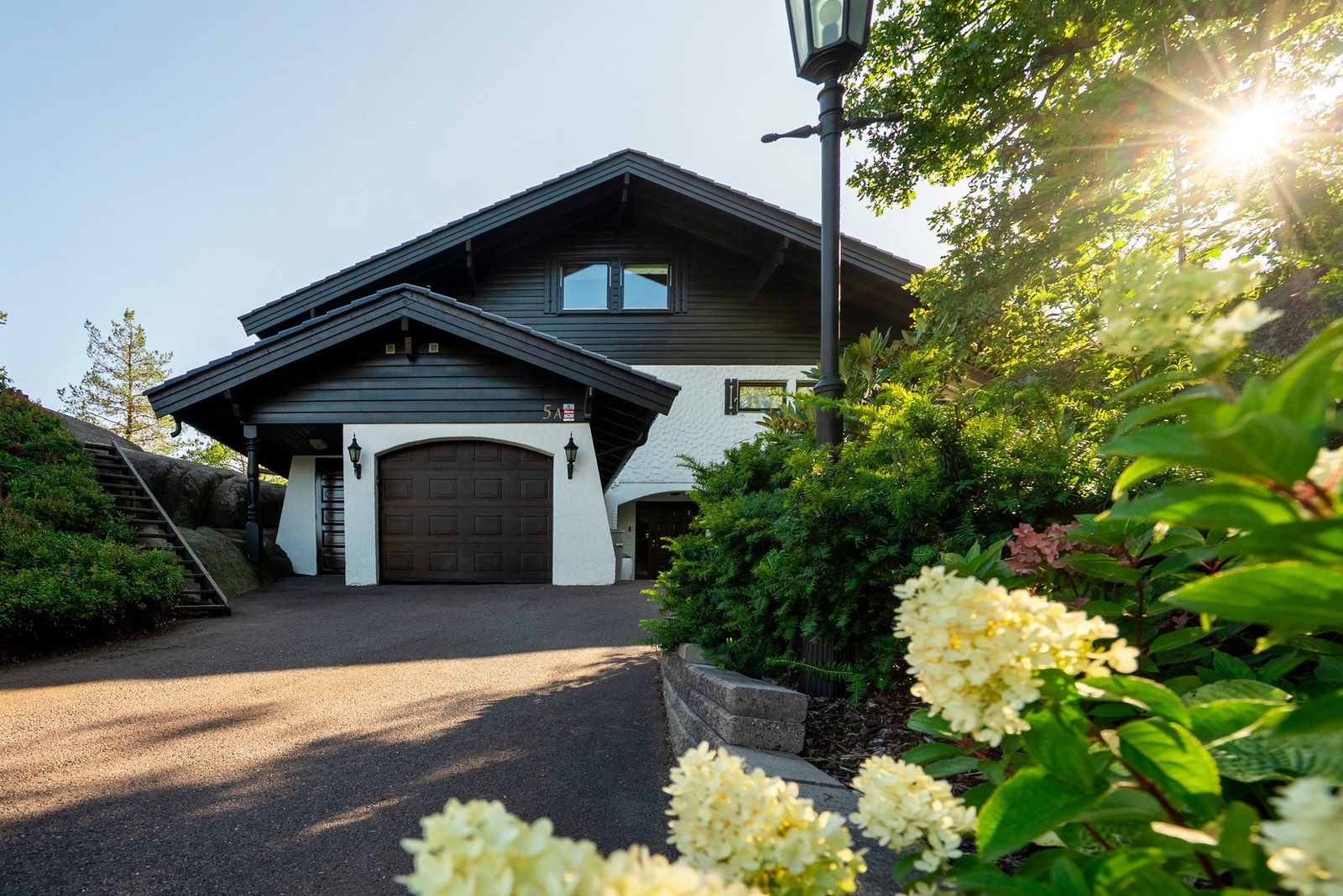 Velstelt oppkjørsel med beplantning og god plass til biloppstilling. Garasje og trapp til hagen gjør hverdagen enkel og tilgjengelig Galleribilde