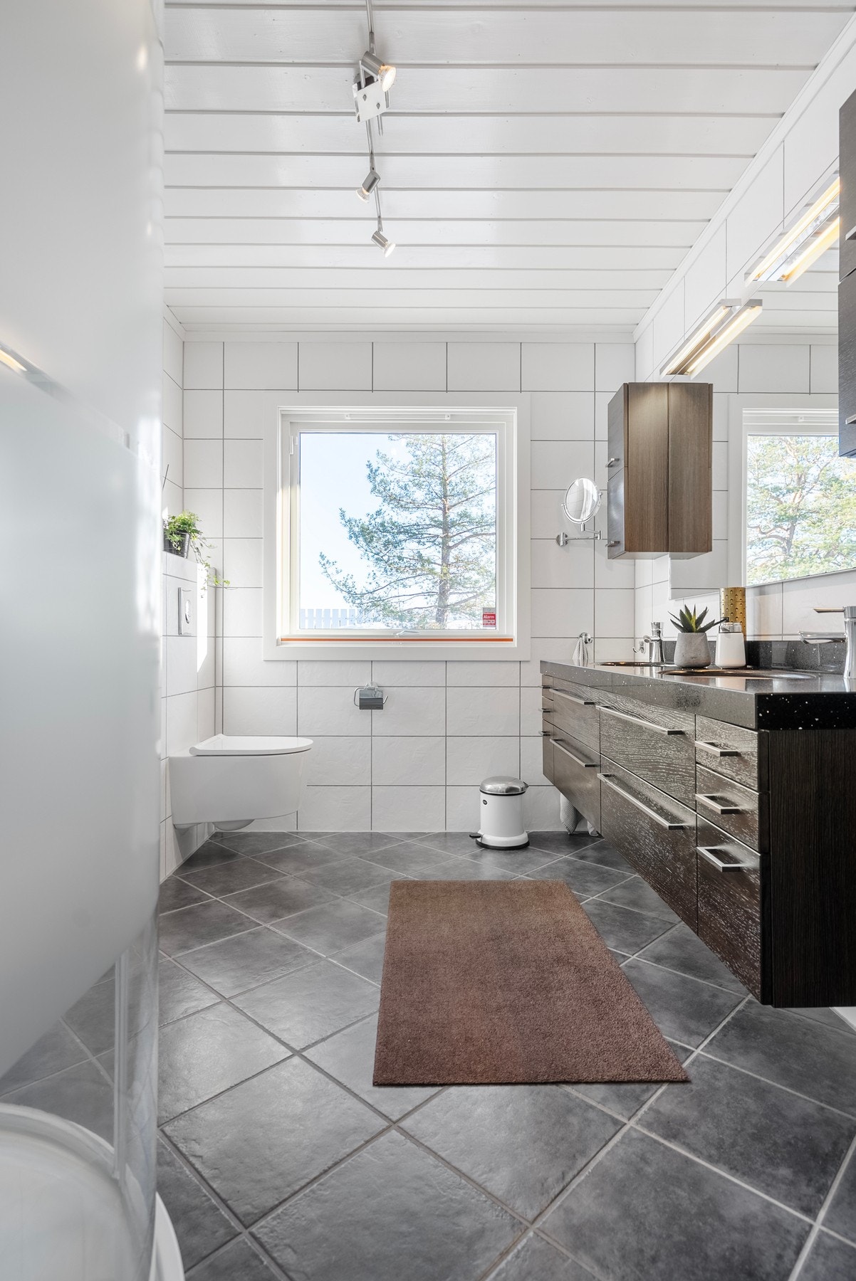 Det romslige baderommet har god takhøyde, naturlig dagslys og et moderne uttrykk. Galleribilde