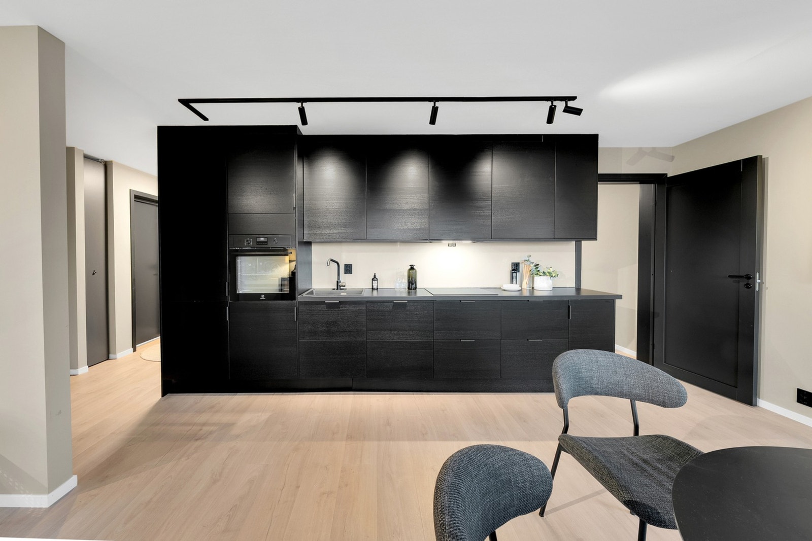 Lekkert kjøkken med mørke eikefronter og integrert kjøl-/fryseskap, oppvaskmaskin, platetopp og stekeovn i praktisk høyde. Galleribilde