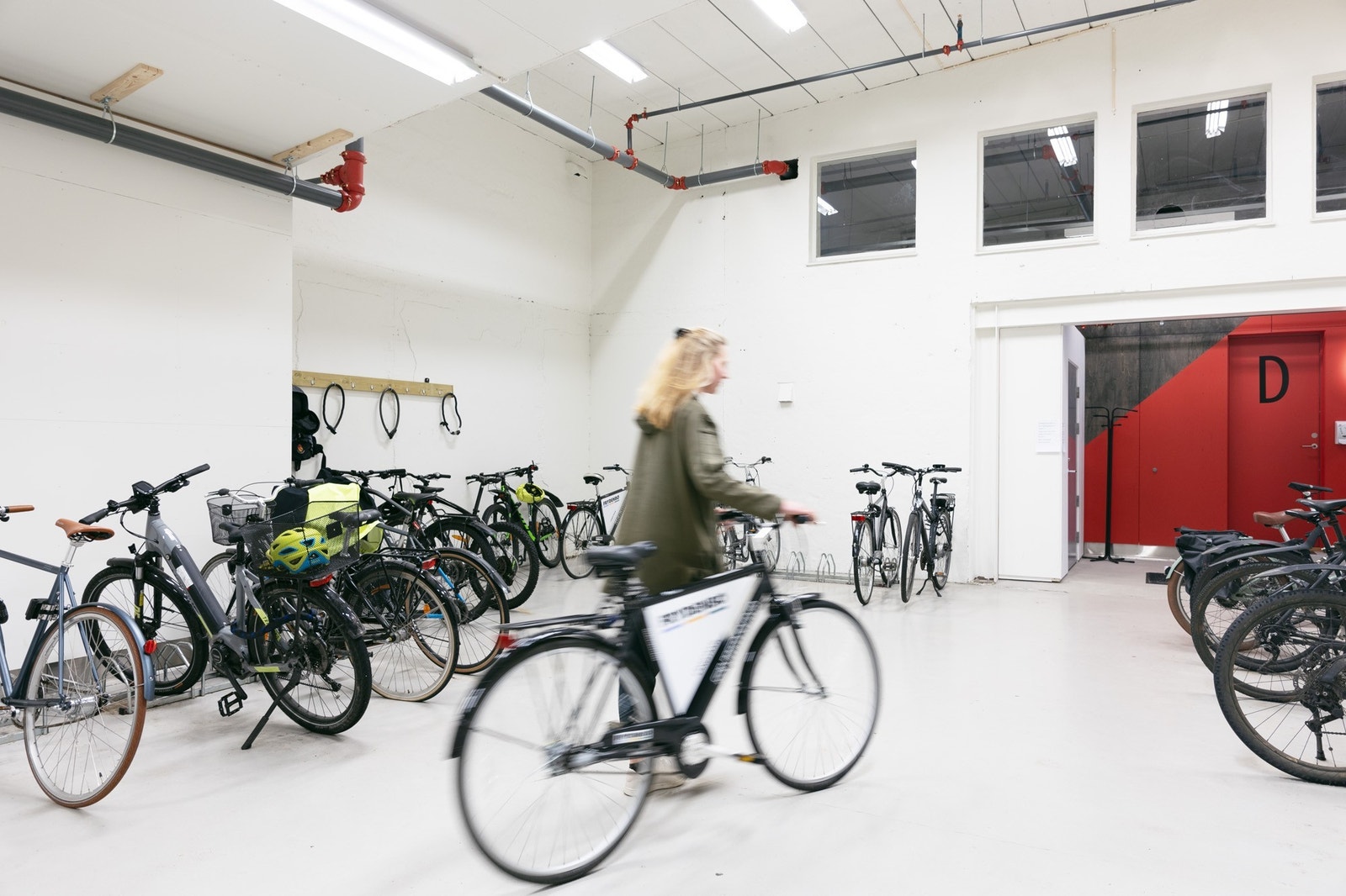 Innendørs sykkelparkering med sykkelvask og garderobe med dusj. Galleribilde