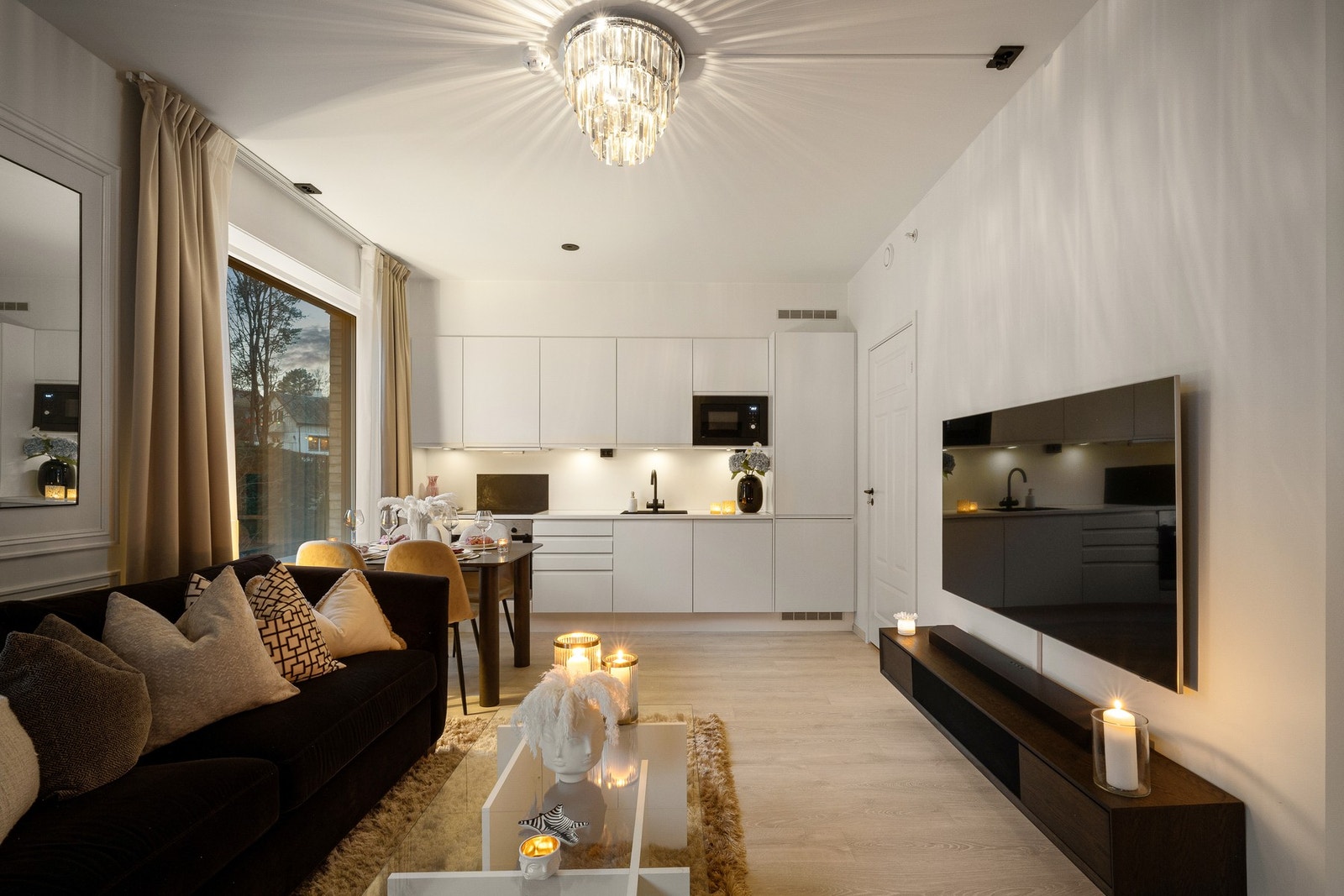 Den åpne løsningen mot kjøkkenet skaper et sosialt og fleksibelt oppholdsrom, der det er lett å møblere med både sofagruppe og spiseplass. Galleribilde