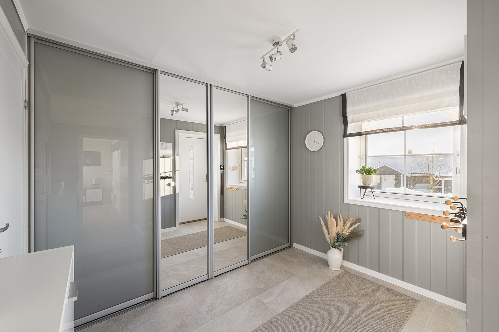 I entréen er det rikelig med plass til yttertøy i stor skyvedørsgarderobe. Boligen fikk ny ytterdør og garasjeport i 2025. Galleribilde