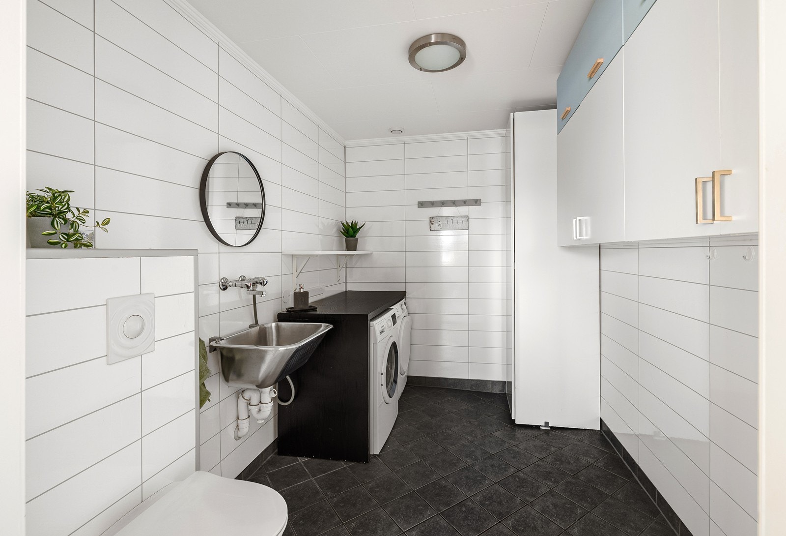 Etasjen har et praktisk vaskerom med fliser på gulv og baderomsplater på vegger. Innredningen består av et underskap/overskap og utslagsvask. I tillegg er det opplegg for vaskemaskin/tørketrommel og det er tilkoblet et vannklosett. Galleribilde