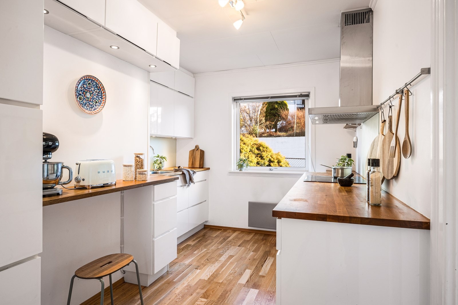 Flott kjøkken i hvit utførelse med glatte fronter og heltre benkeplate. Galleribilde